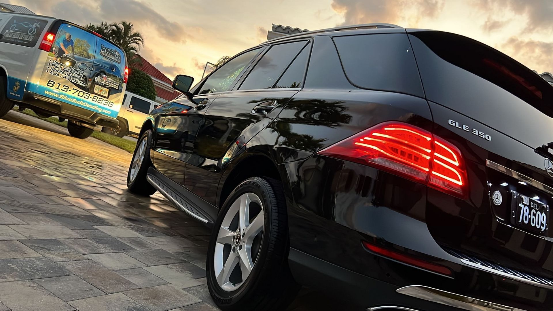 A black car is parked next to a white van.