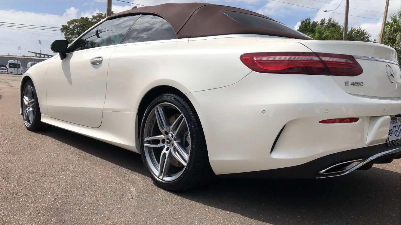 A white mercedes benz e class convertible is parked on the side of the road.
