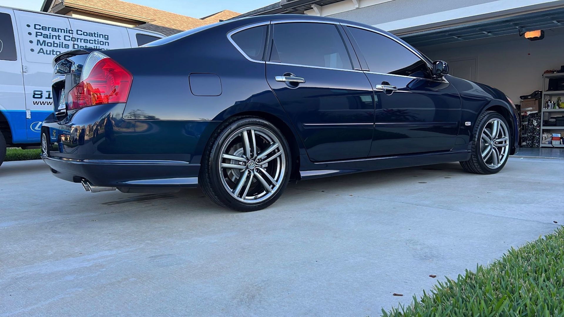 A black car is parked in a driveway in front of a garage.