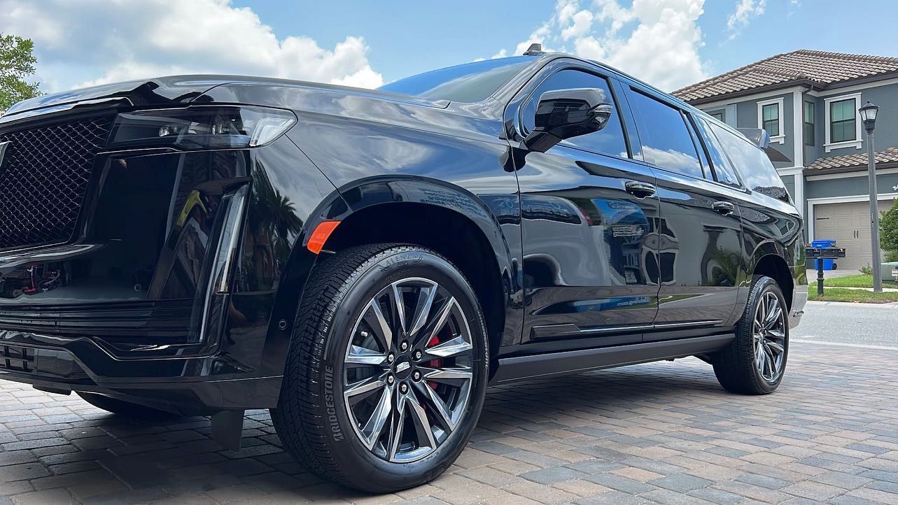 A black suv is parked in front of a house.