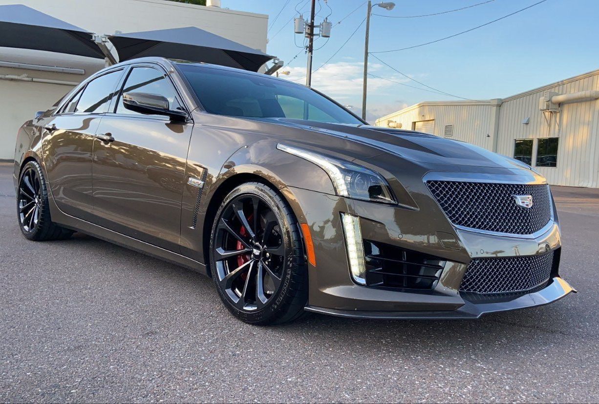 A cadillac cts is parked in front of a building.