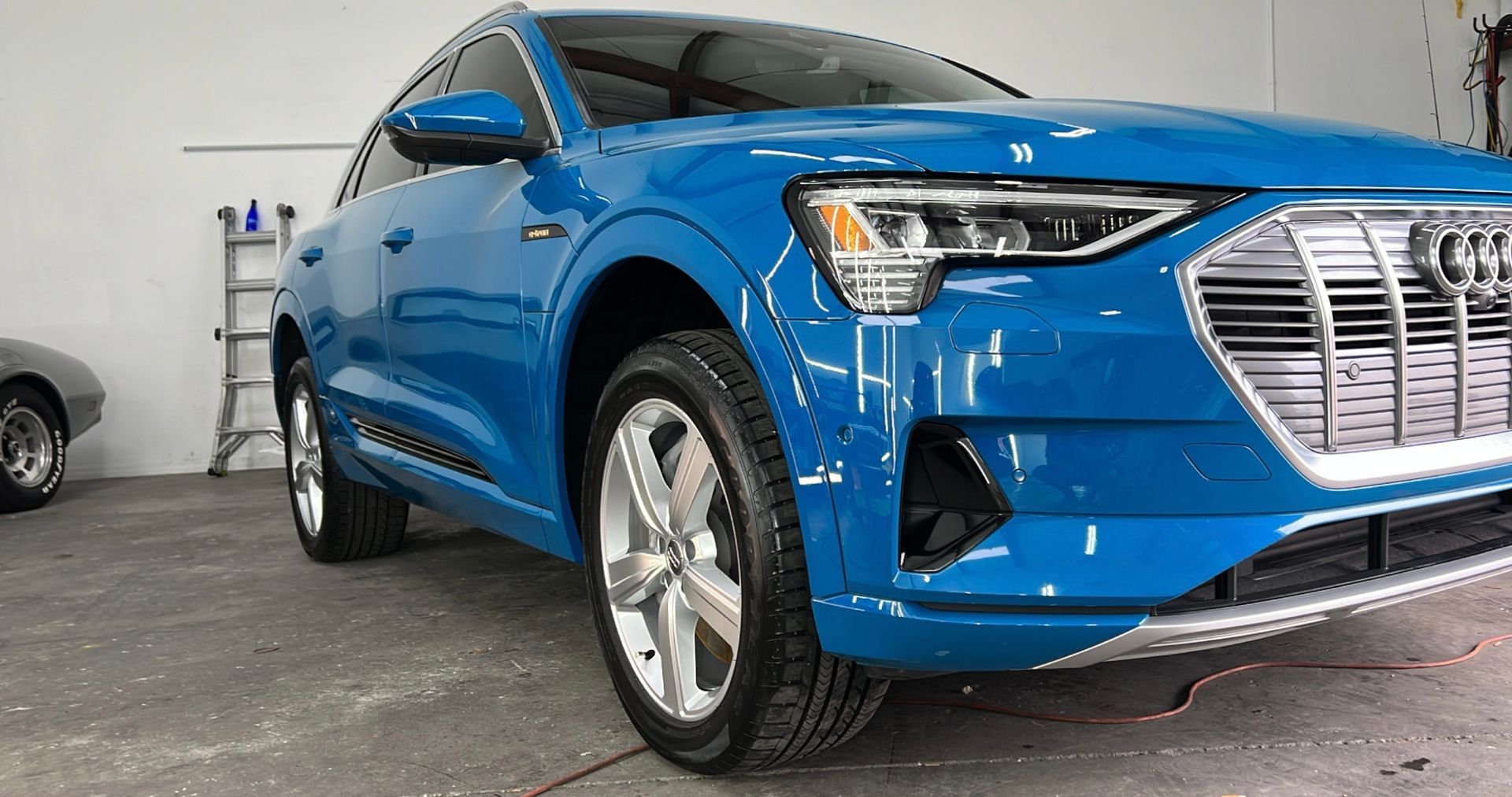 A blue audi e-tron is parked in a garage.