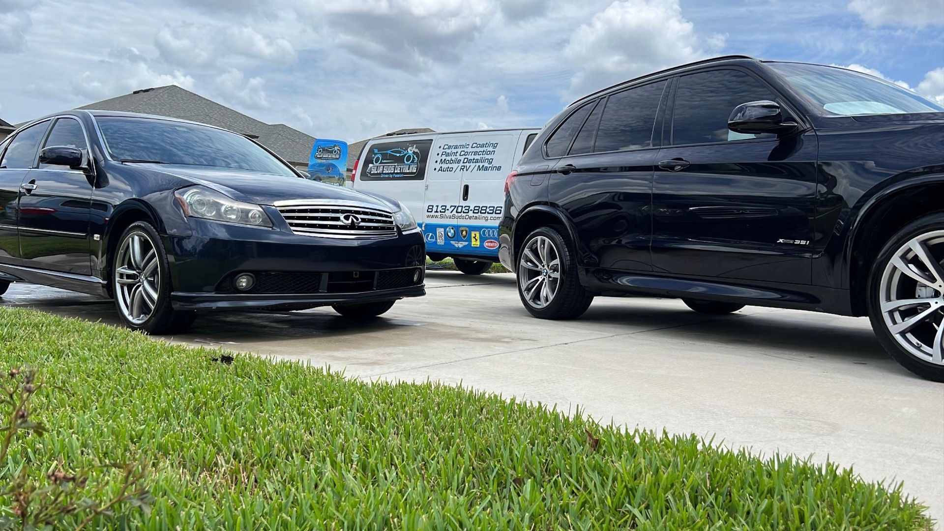 Two black cars are parked next to each other in a driveway.