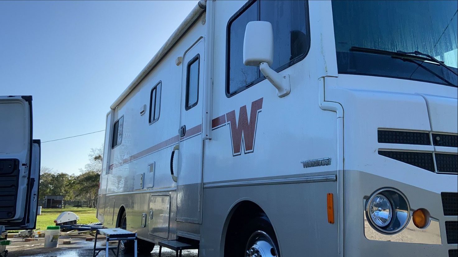 A white rv with the letter w painted on the side is parked in a parking lot.