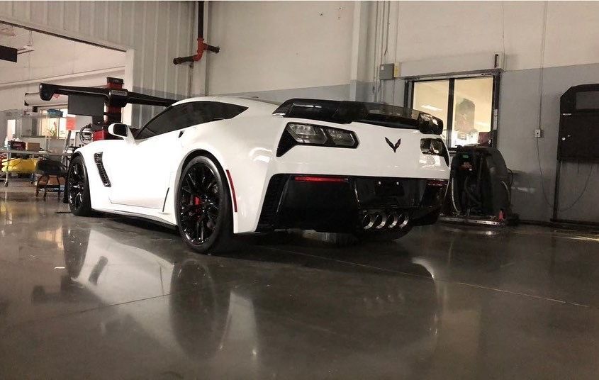 A white sports car is parked in a garage.