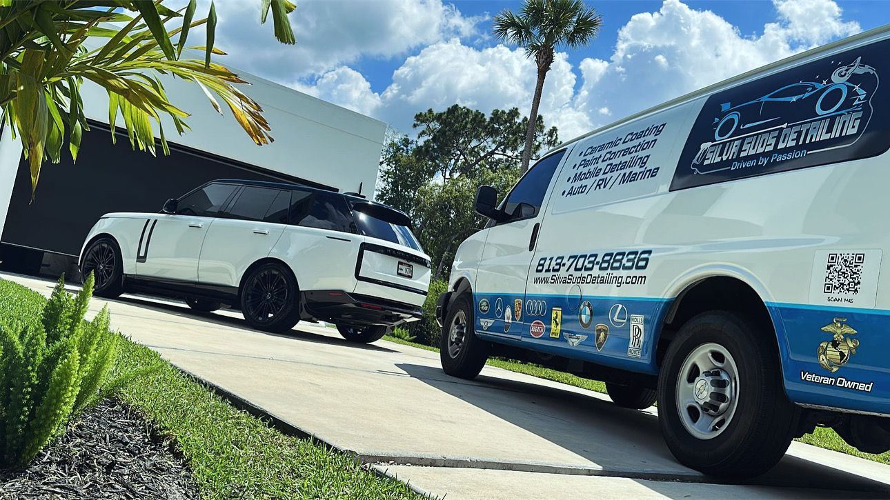 Two vans are parked on the side of the road next to each other.