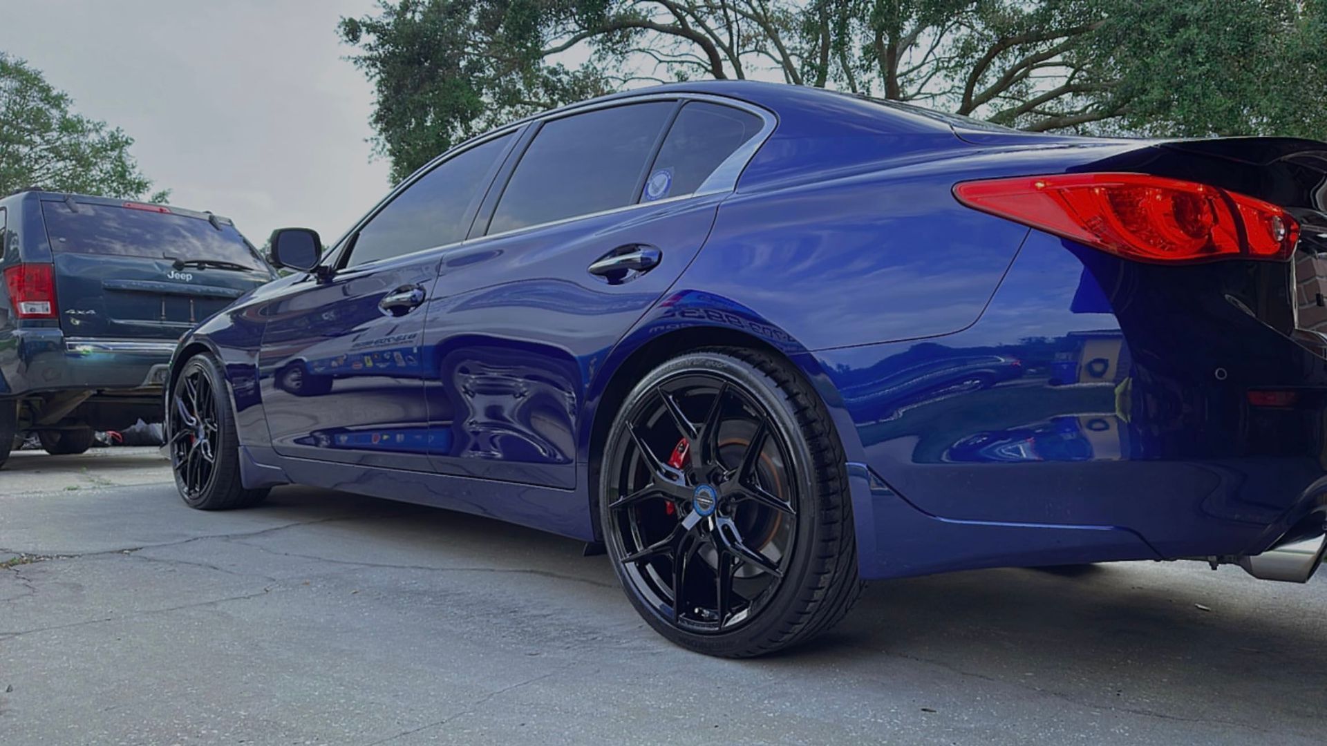 A blue car with black wheels is parked in a parking lot.