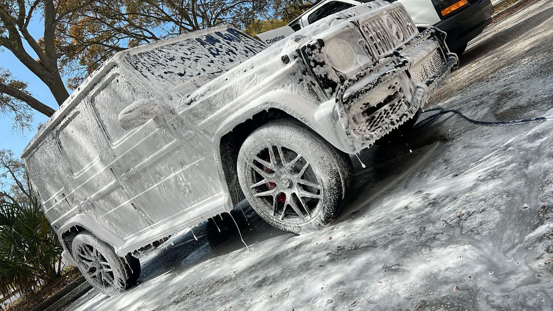 A white suv is covered in foam on the side of the road.