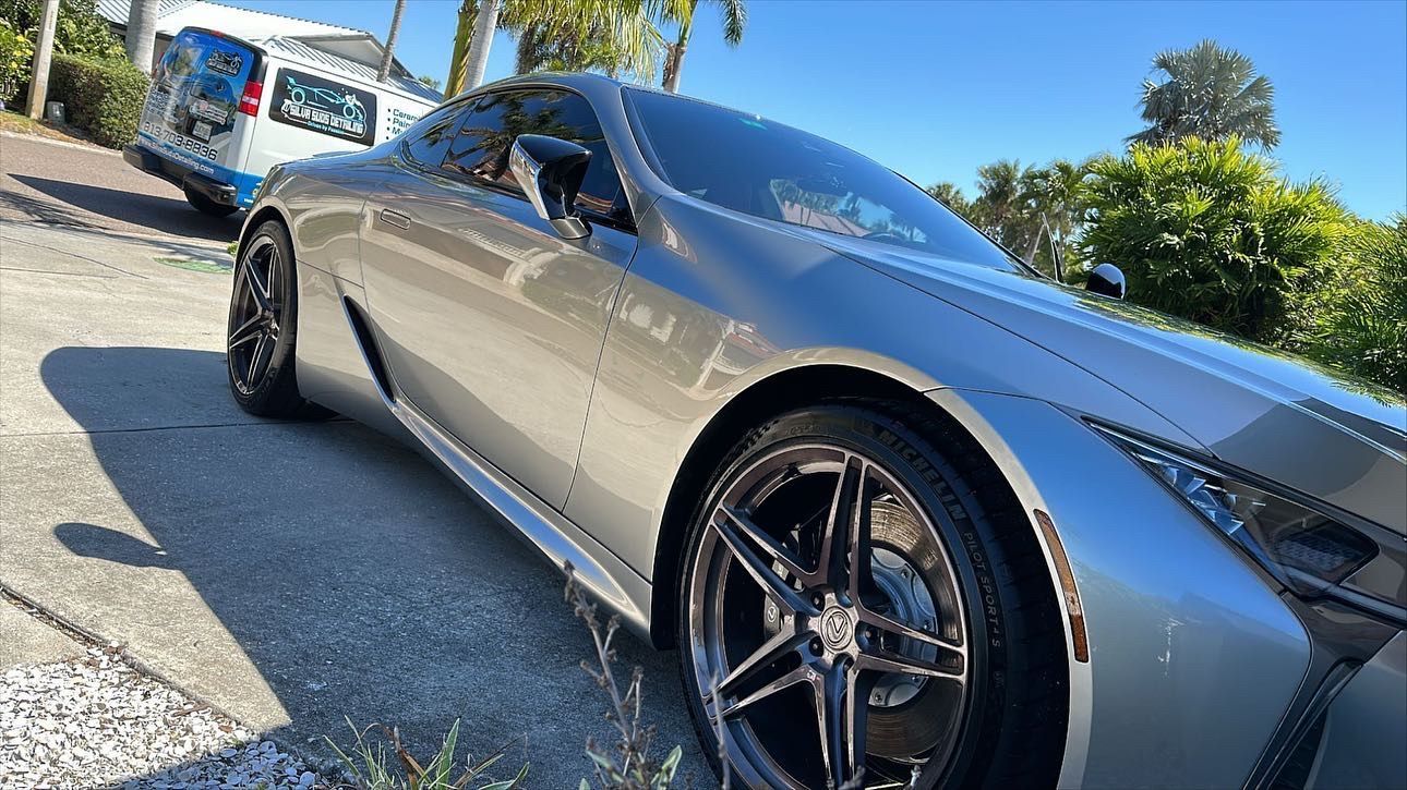 A silver sports car is parked on the side of the road.