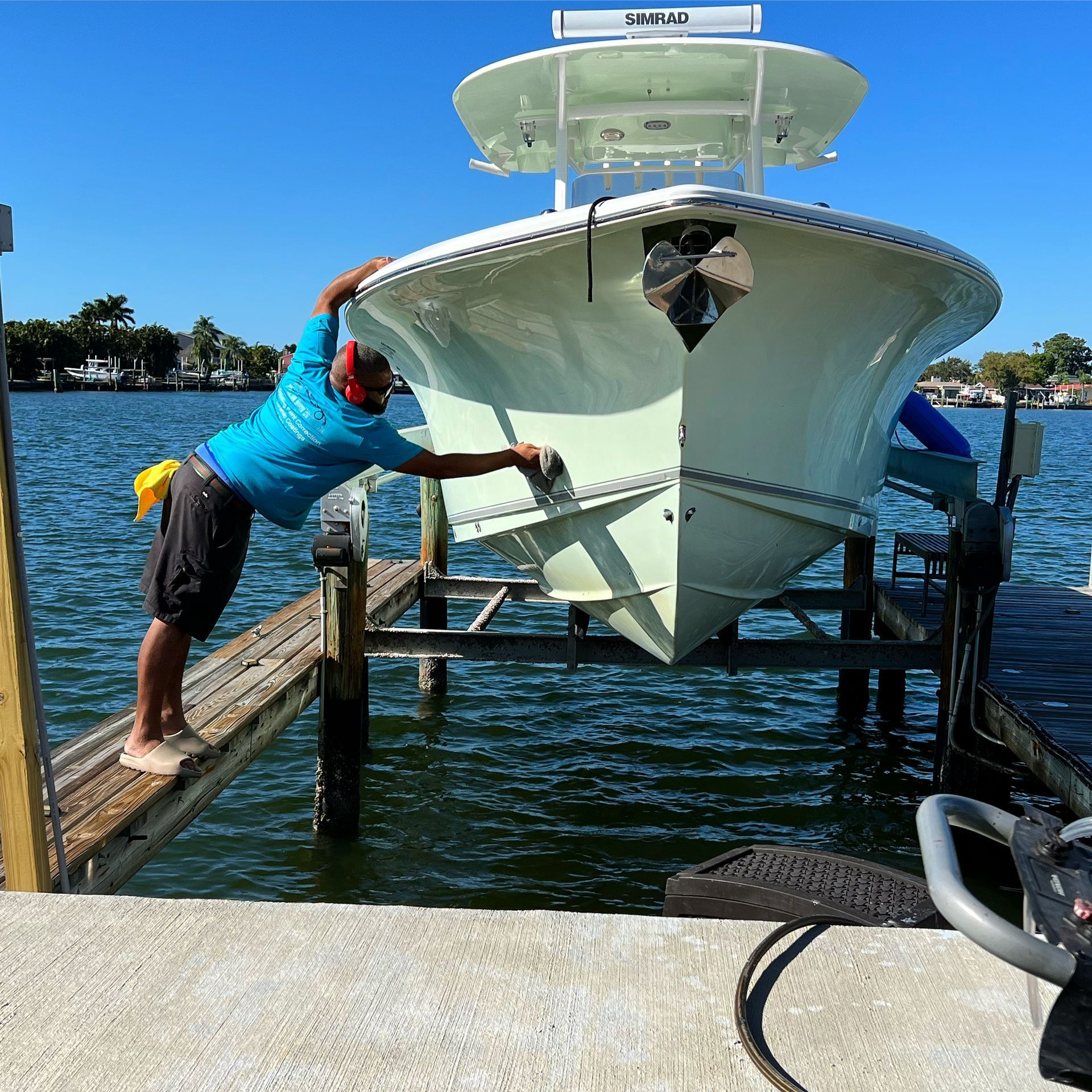 A man in a blue shirt is standing on a dock next to a boat