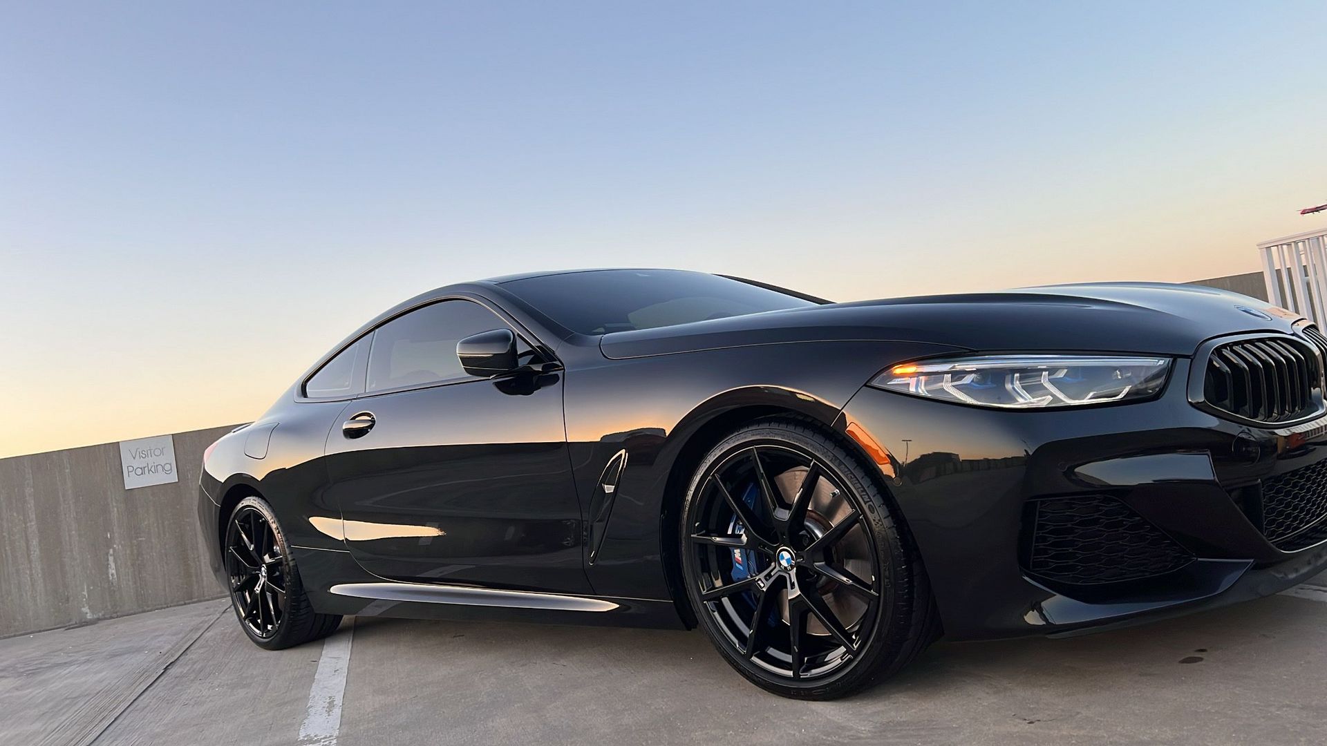 A black bmw m8 coupe is parked in a parking lot.