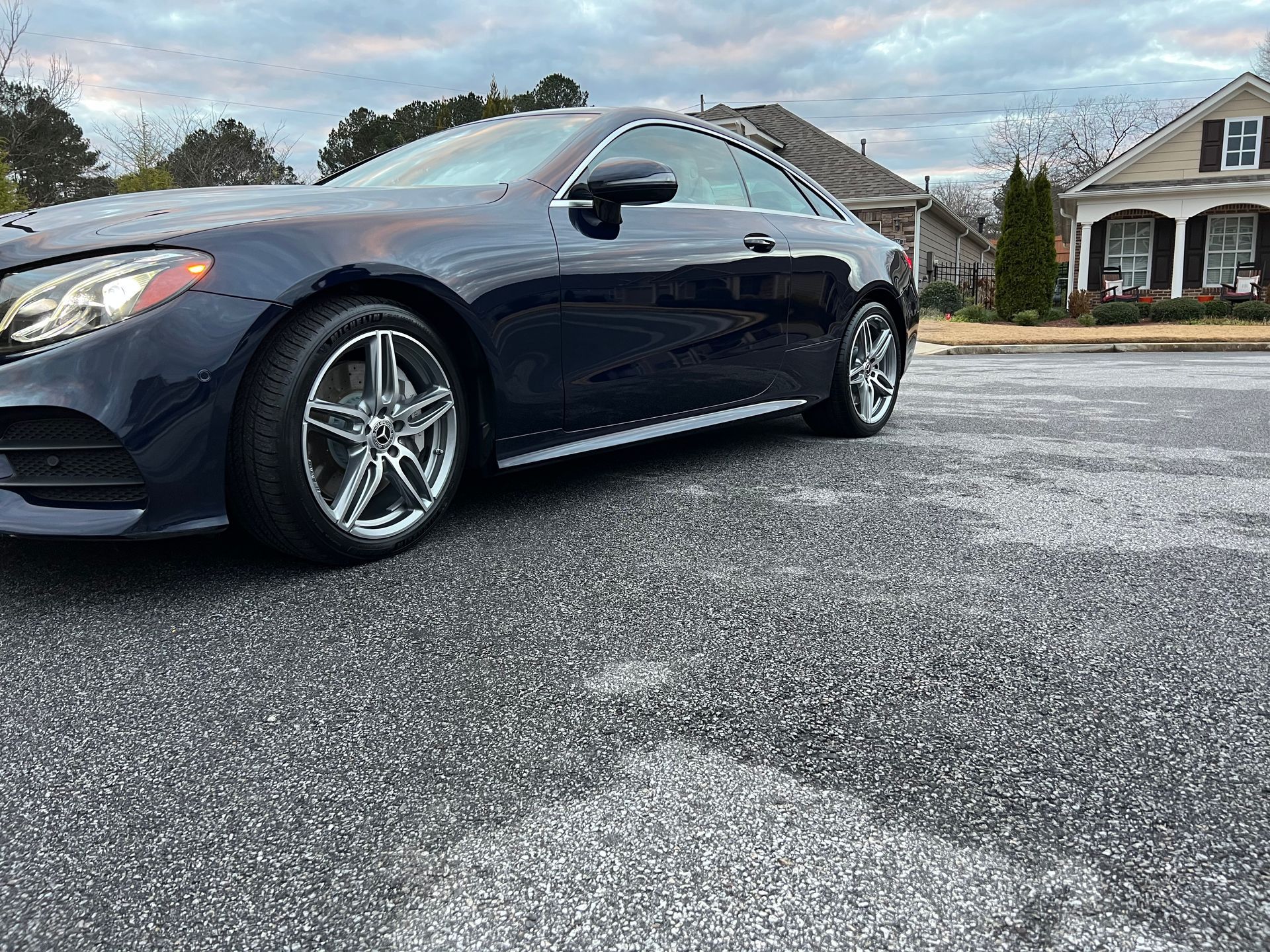 A blue mercedes benz e class coupe is parked in a parking lot.