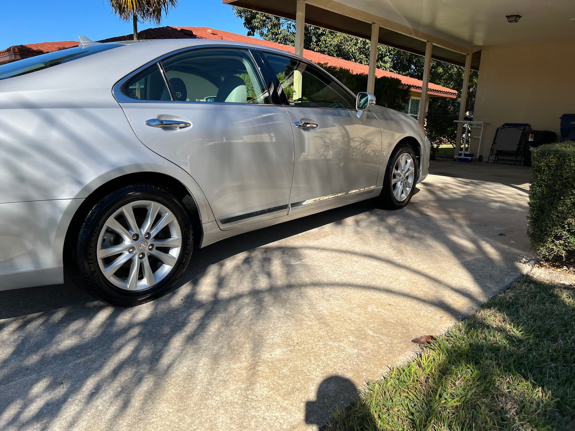 A silver car is parked in a driveway in front of a house.