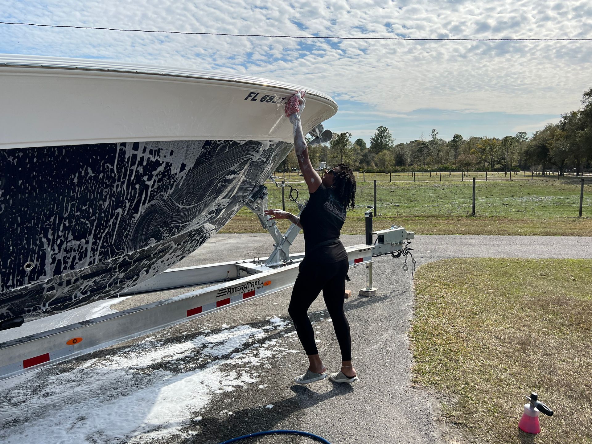 A woman is washing a boat on a trailer.