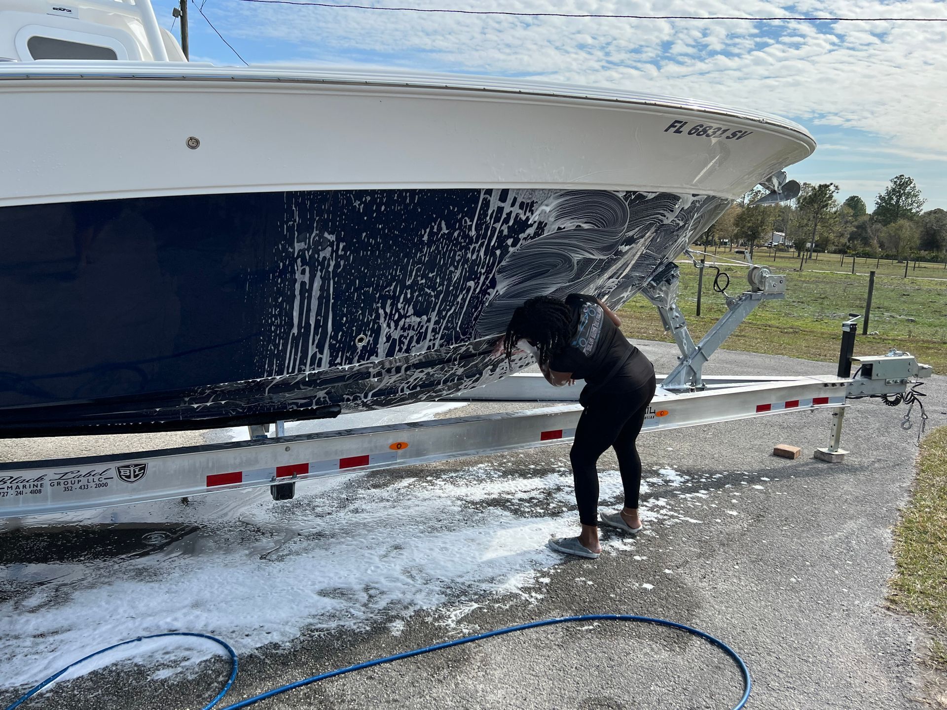 A man is washing a boat on a trailer with a hose.
