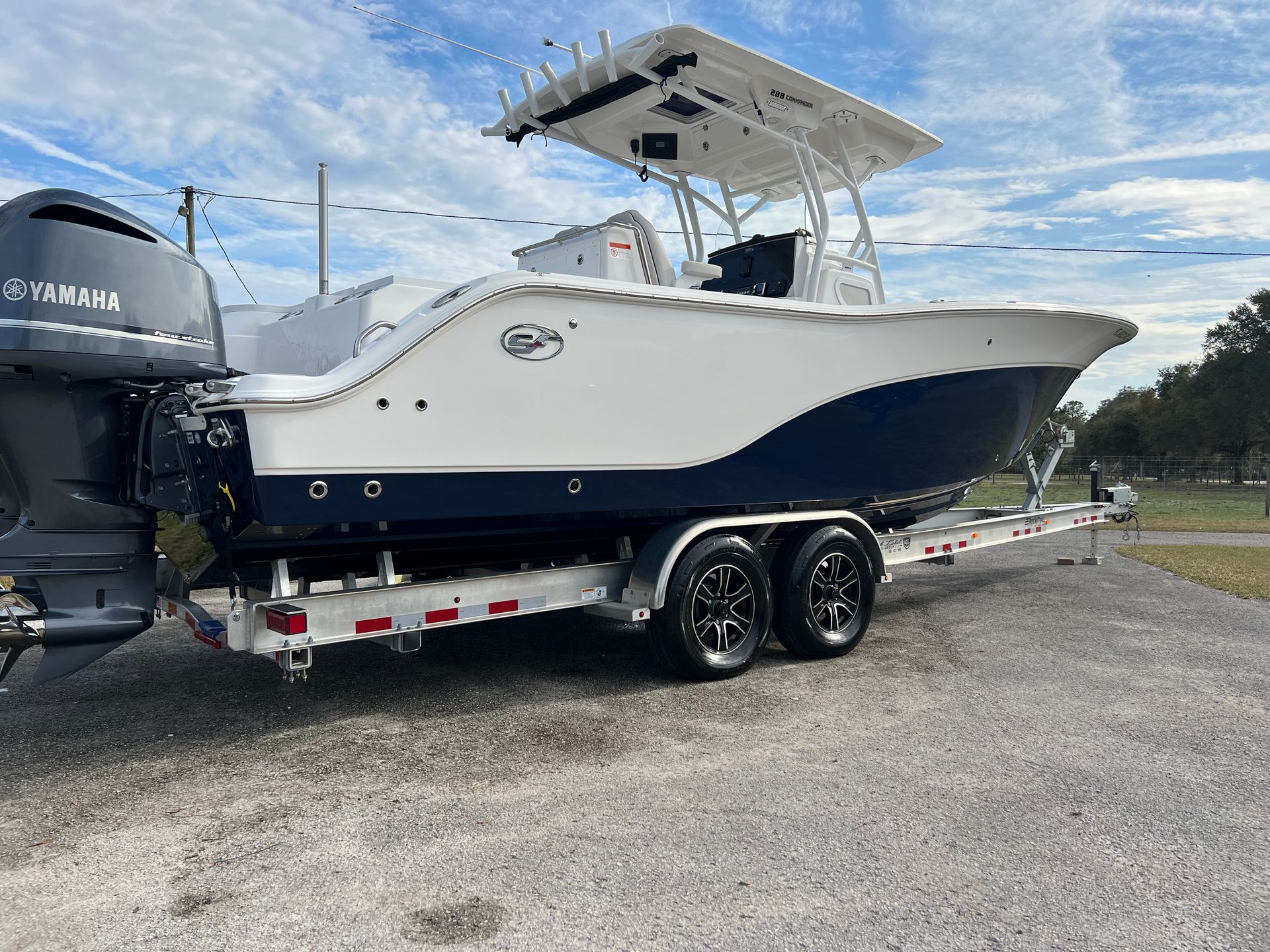 A white and blue boat is parked on a trailer.