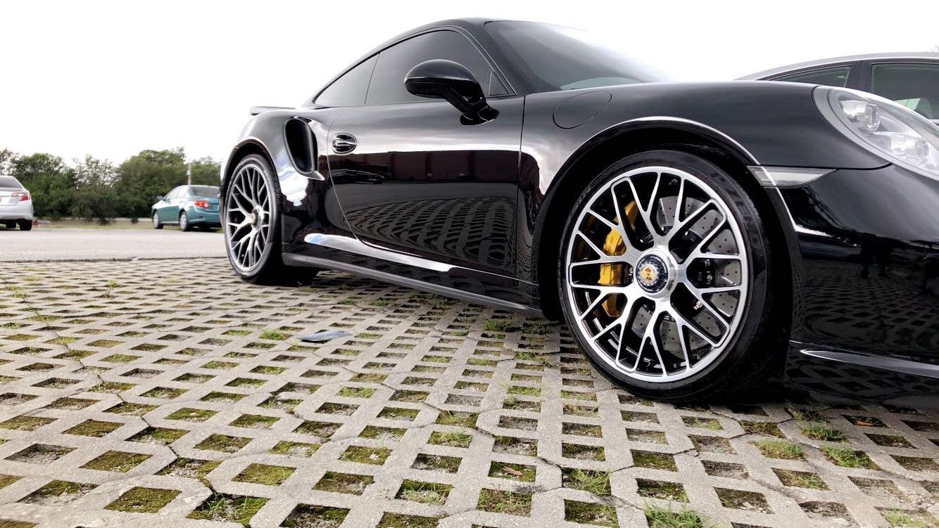 A black sports car is parked in a parking lot.