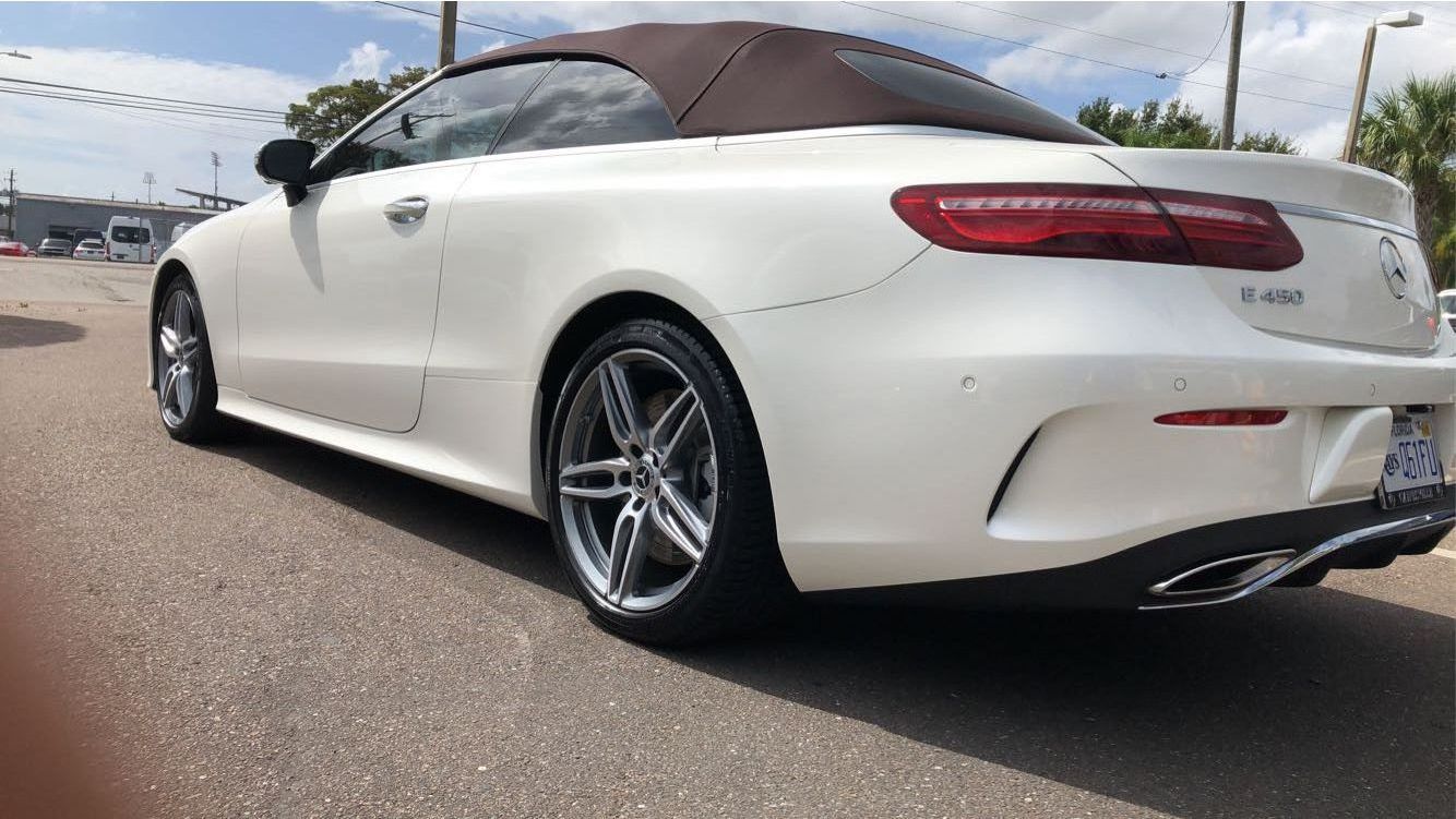 A white mercedes benz e class convertible is parked in a parking lot.