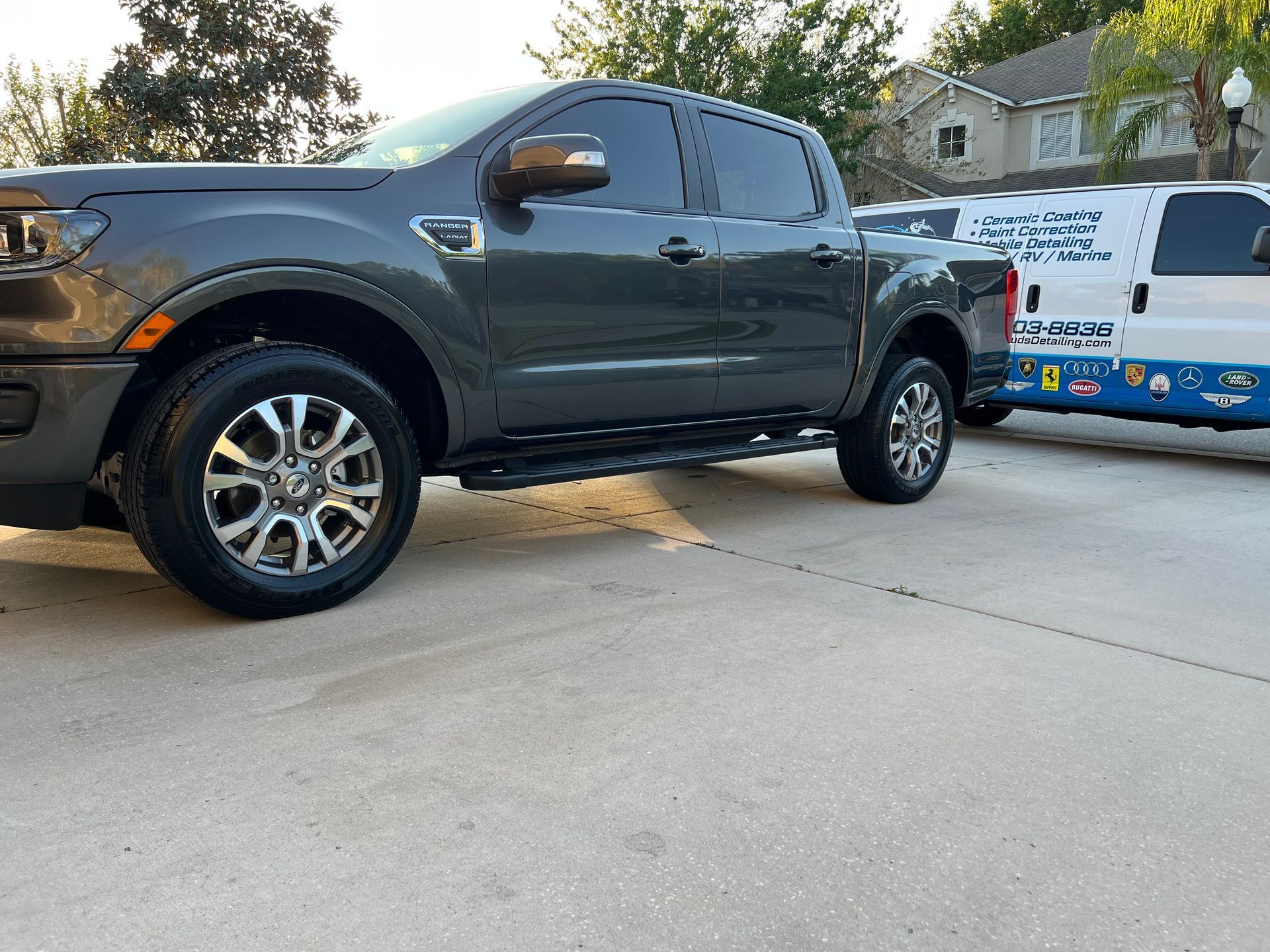 A gray truck is parked next to a white van in a driveway.