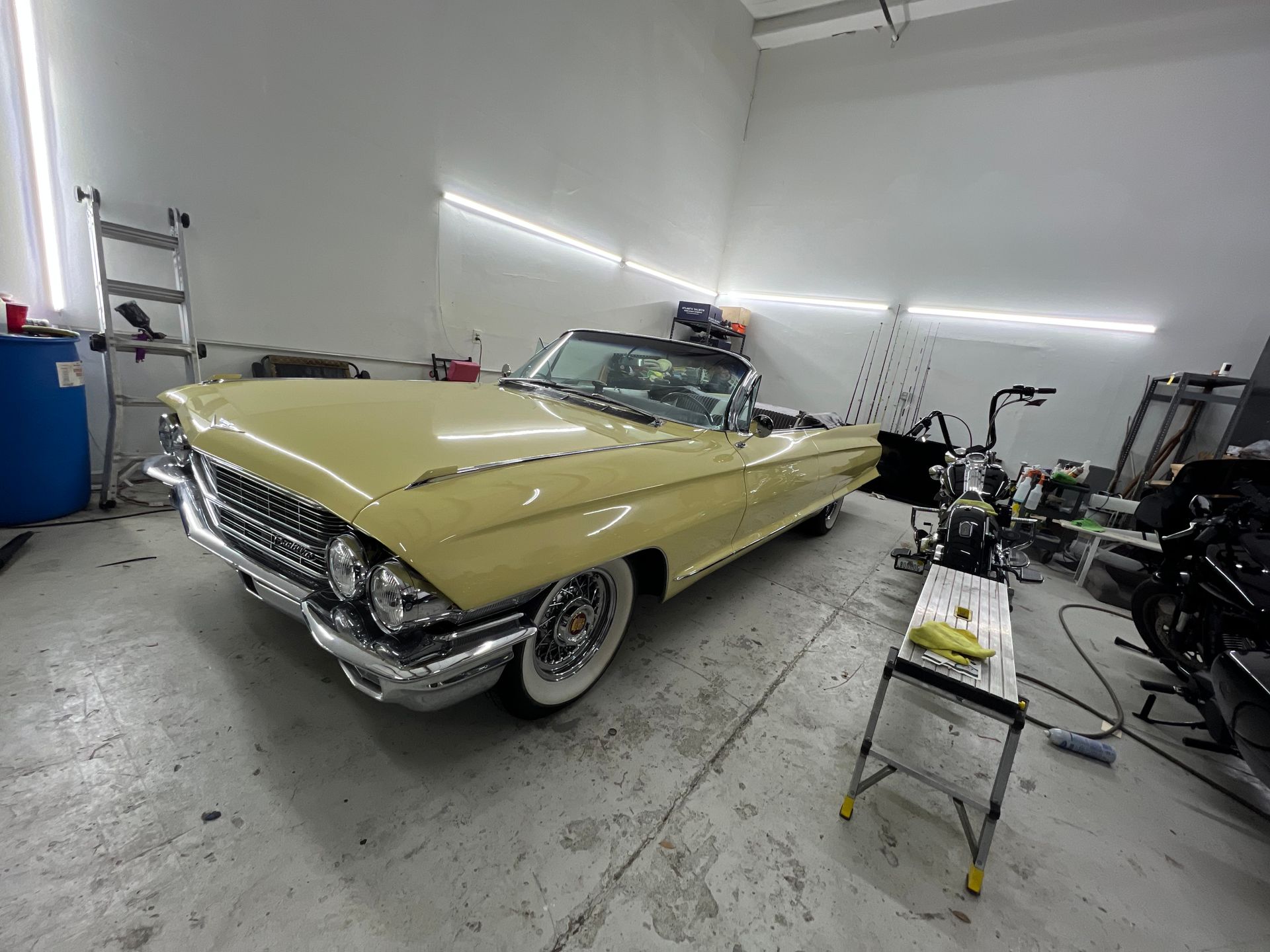 A yellow car is parked in a garage next to a ladder.