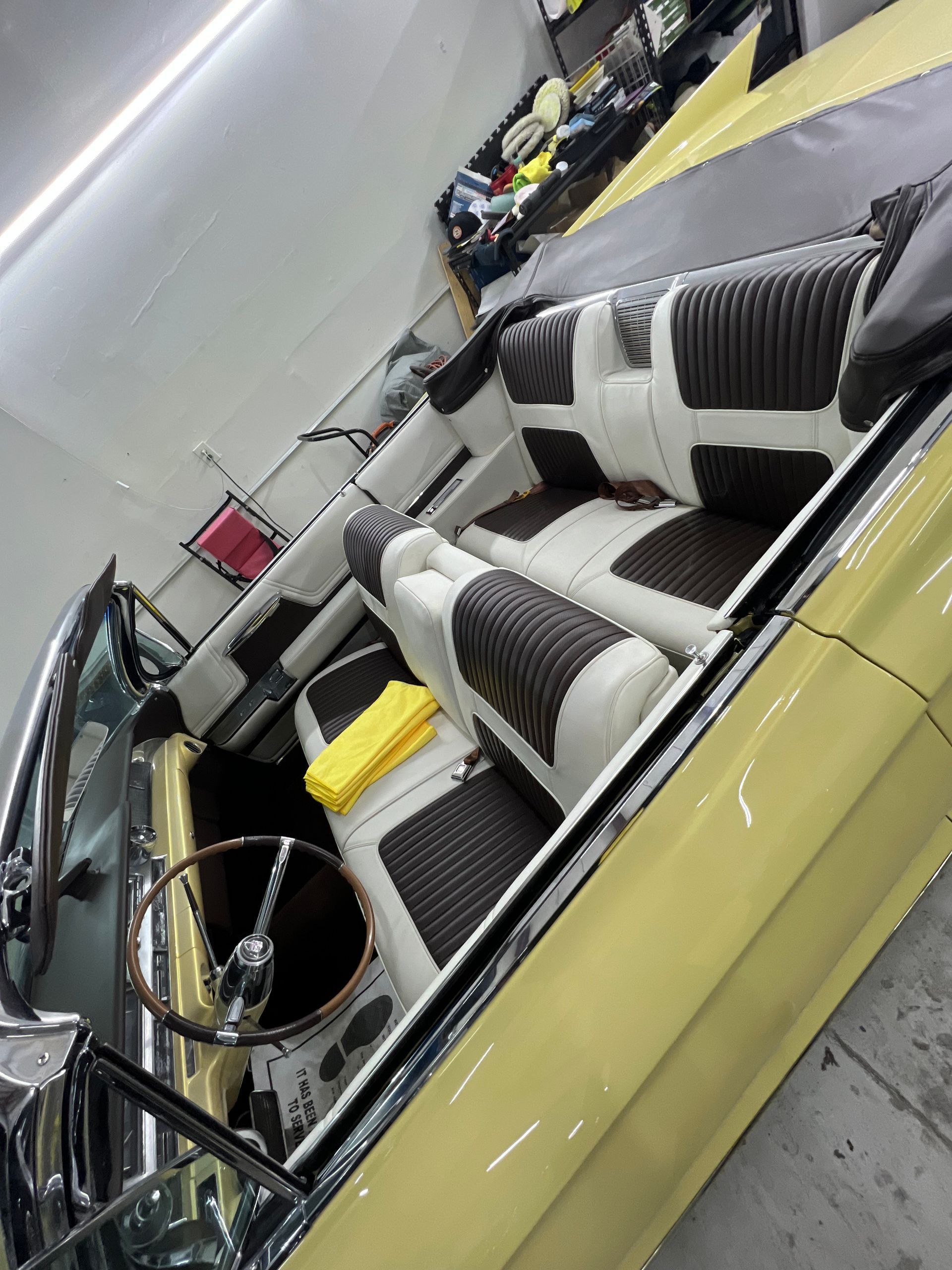 A yellow car with brown and white seats is parked in a garage