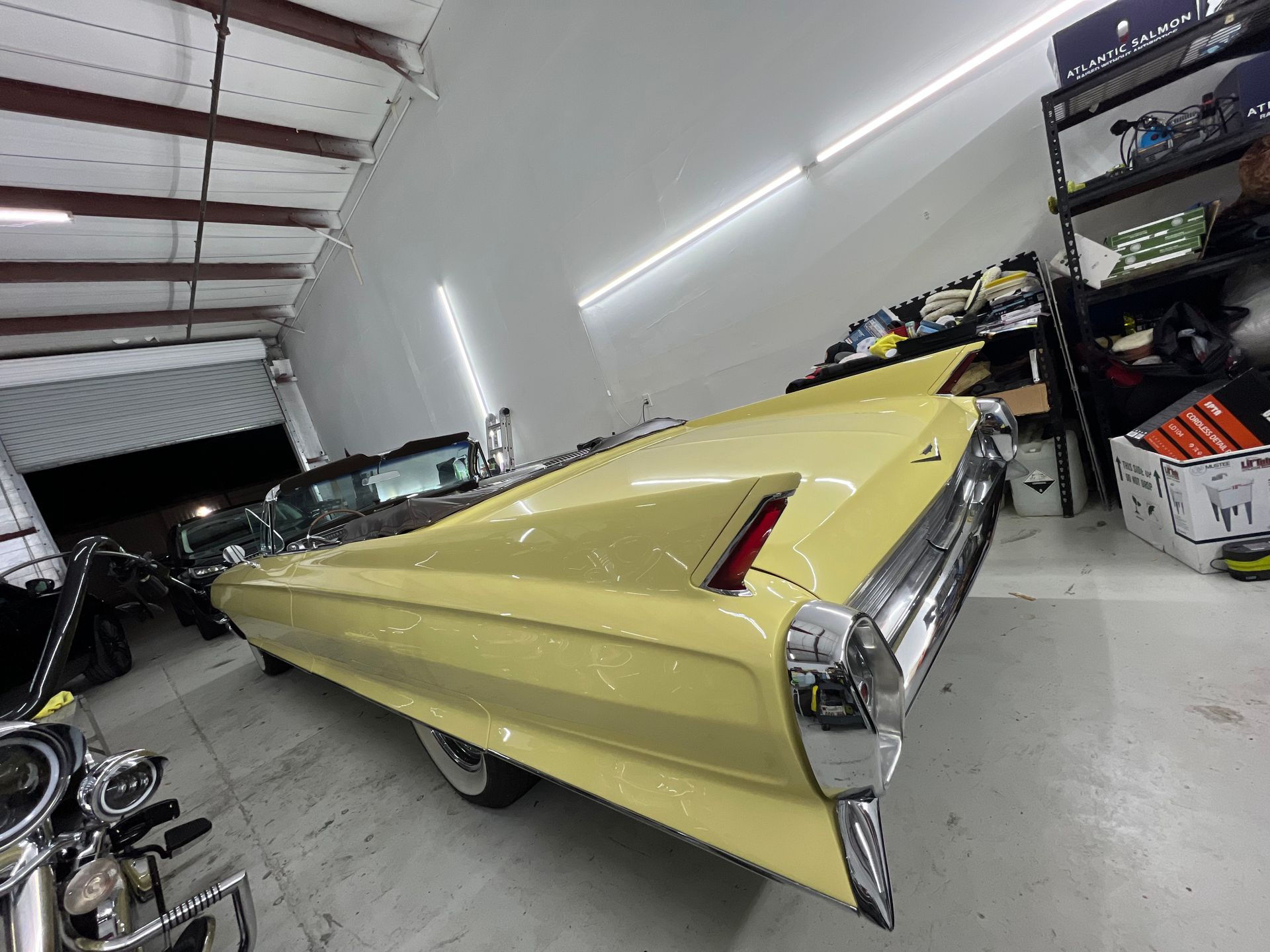 A yellow car is parked in a garage next to a motorcycle.