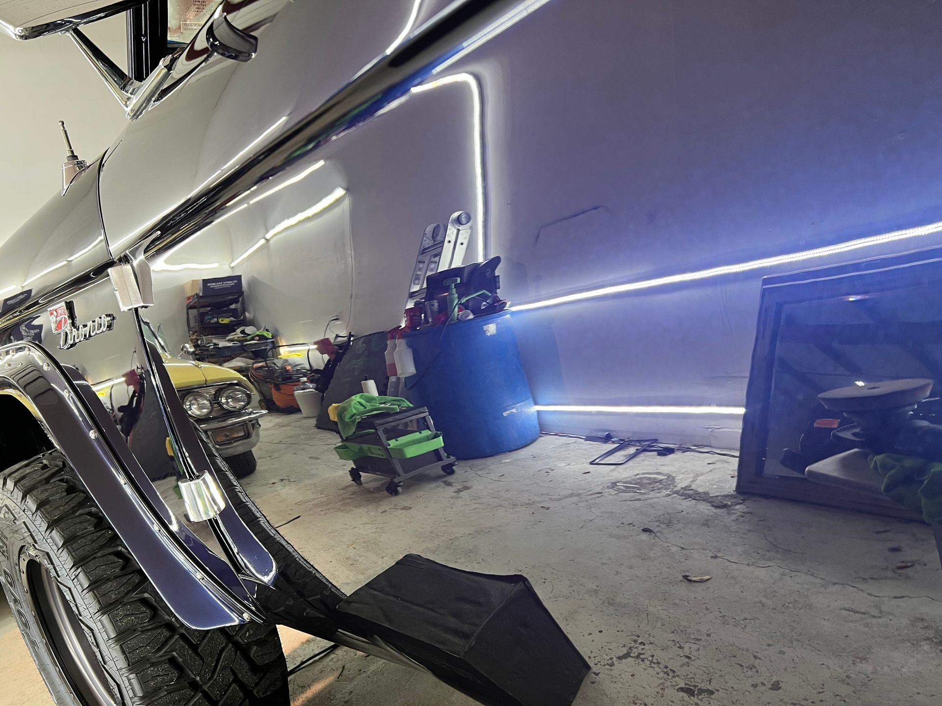 A car is parked in a garage with a lot of lights on the wall.