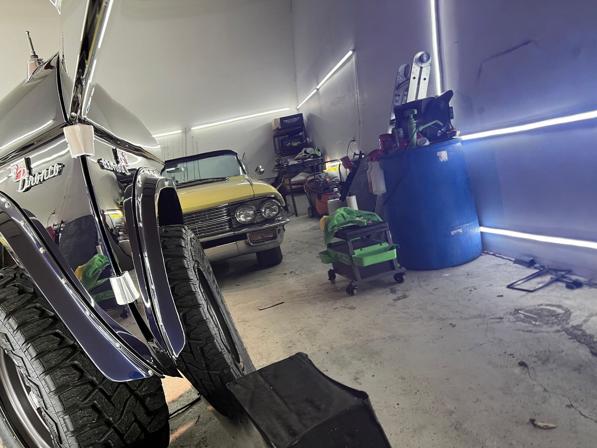 A jeep is parked in a garage next to a yellow car.
