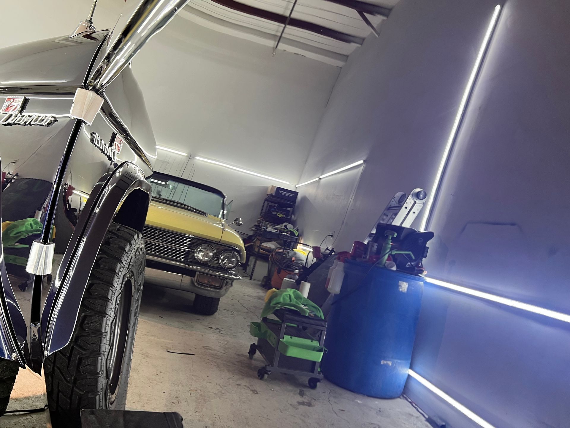 A black truck is parked in a garage next to a yellow truck.