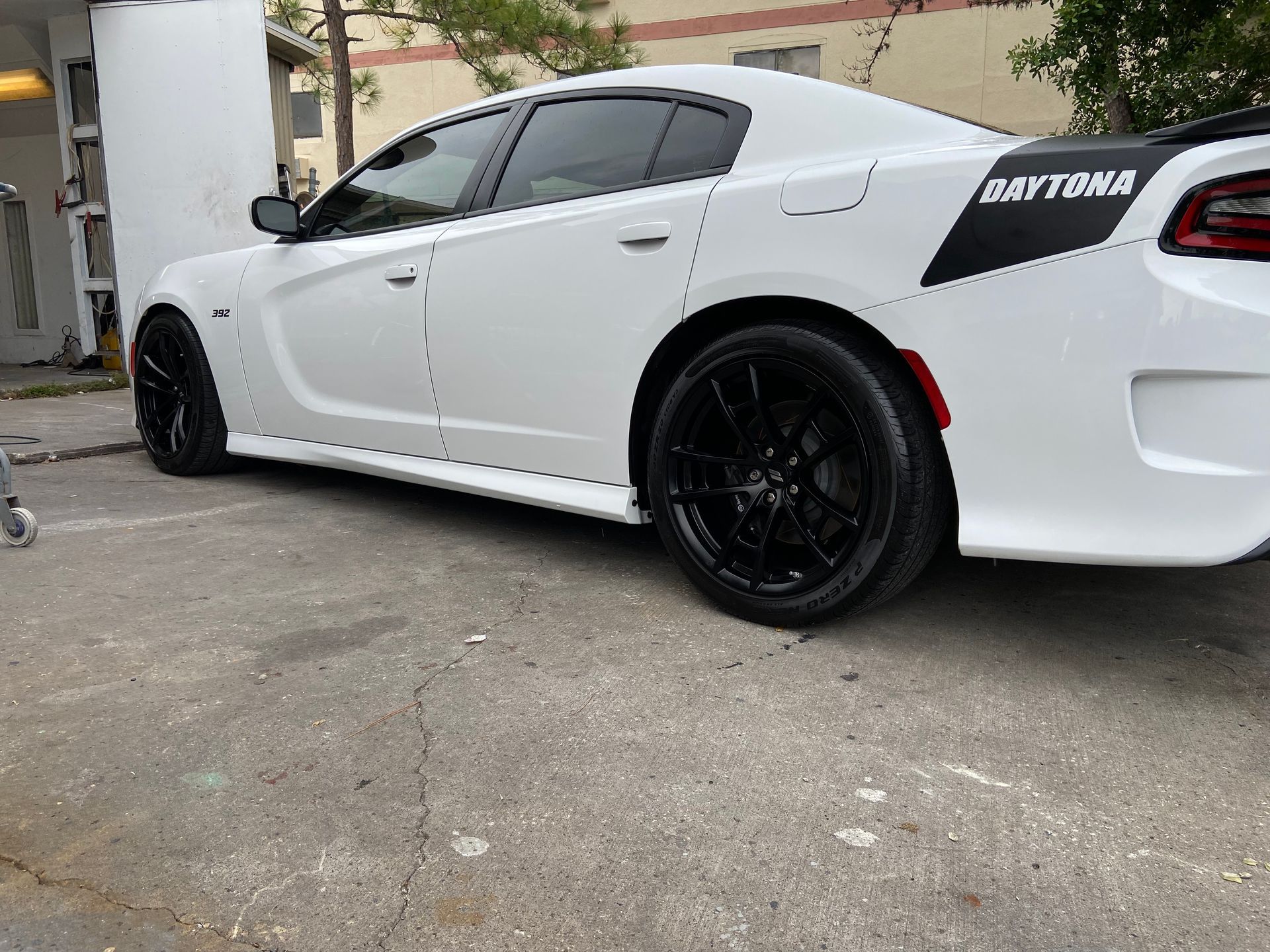 A white dodge charger is parked in a parking lot.