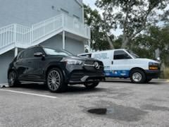 A black suv and a white van are parked in a parking lot in front of a building.