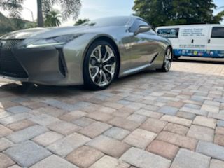 A silver sports car is parked on a brick driveway.