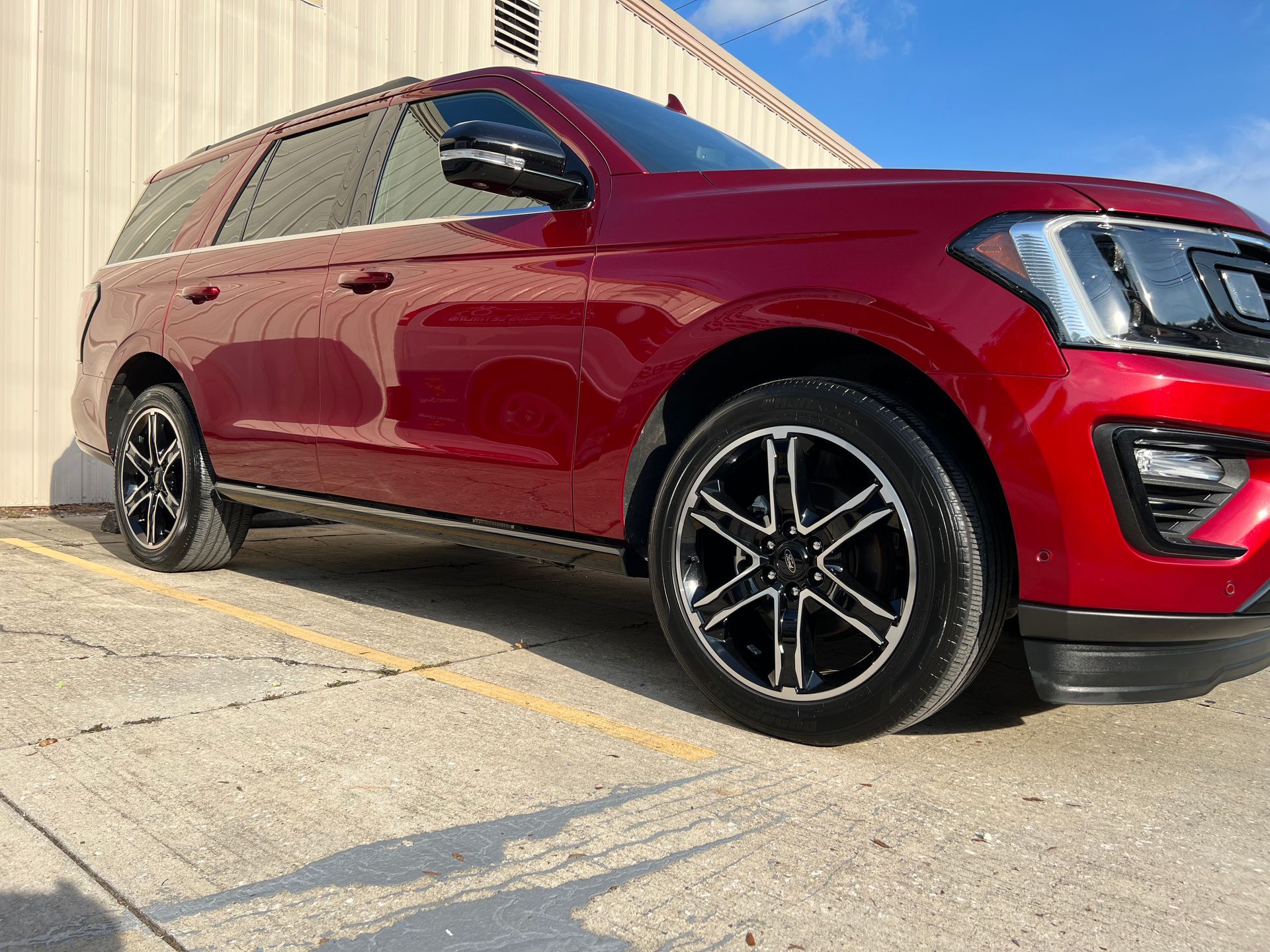 A red ford expedition is parked in a parking lot.