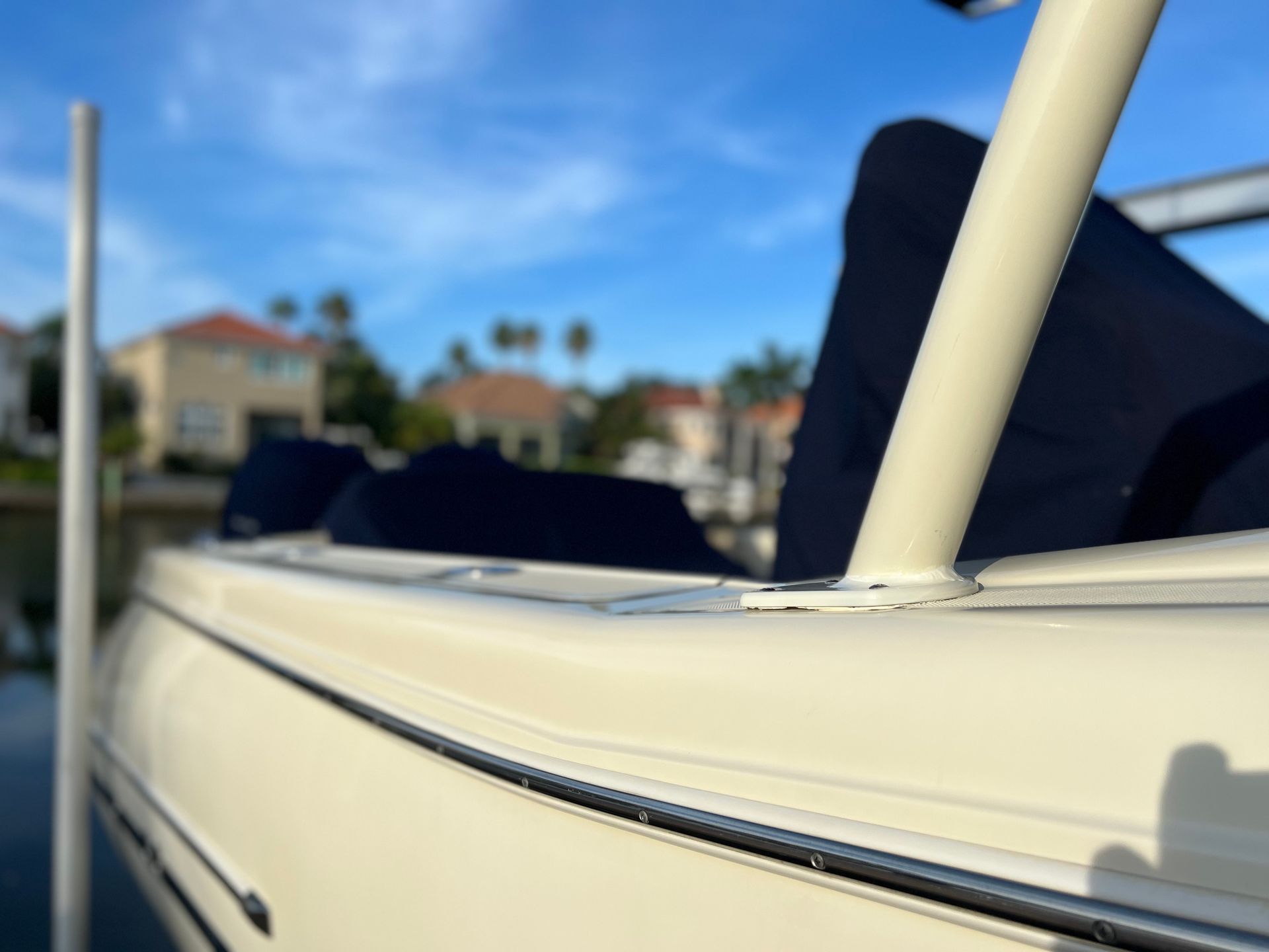 A white boat is docked in a marina with a blue cover on it