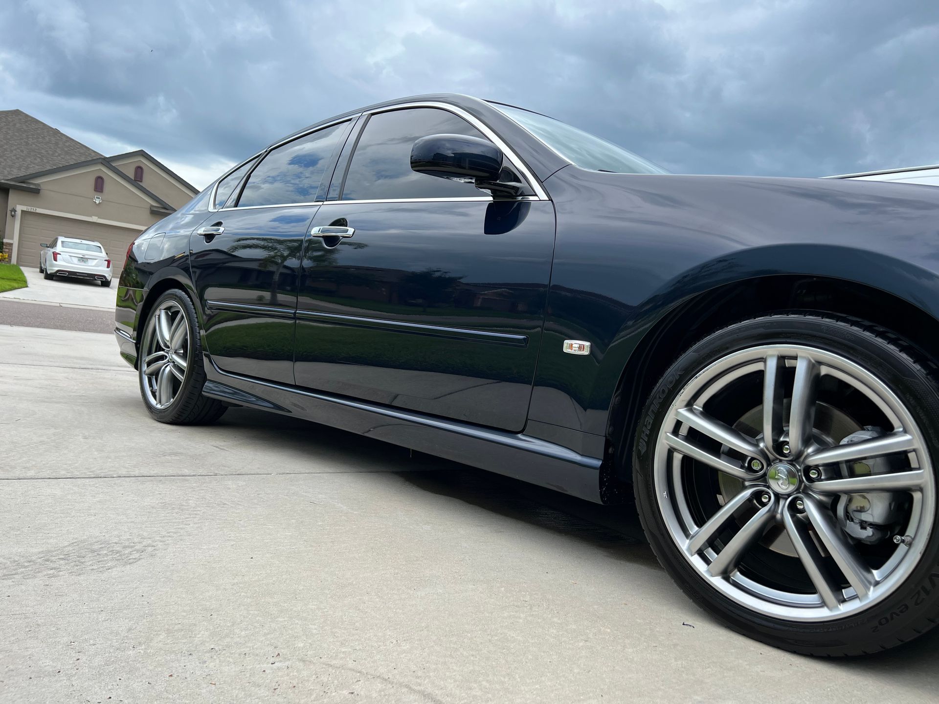 A black car is parked in a driveway in front of a house.