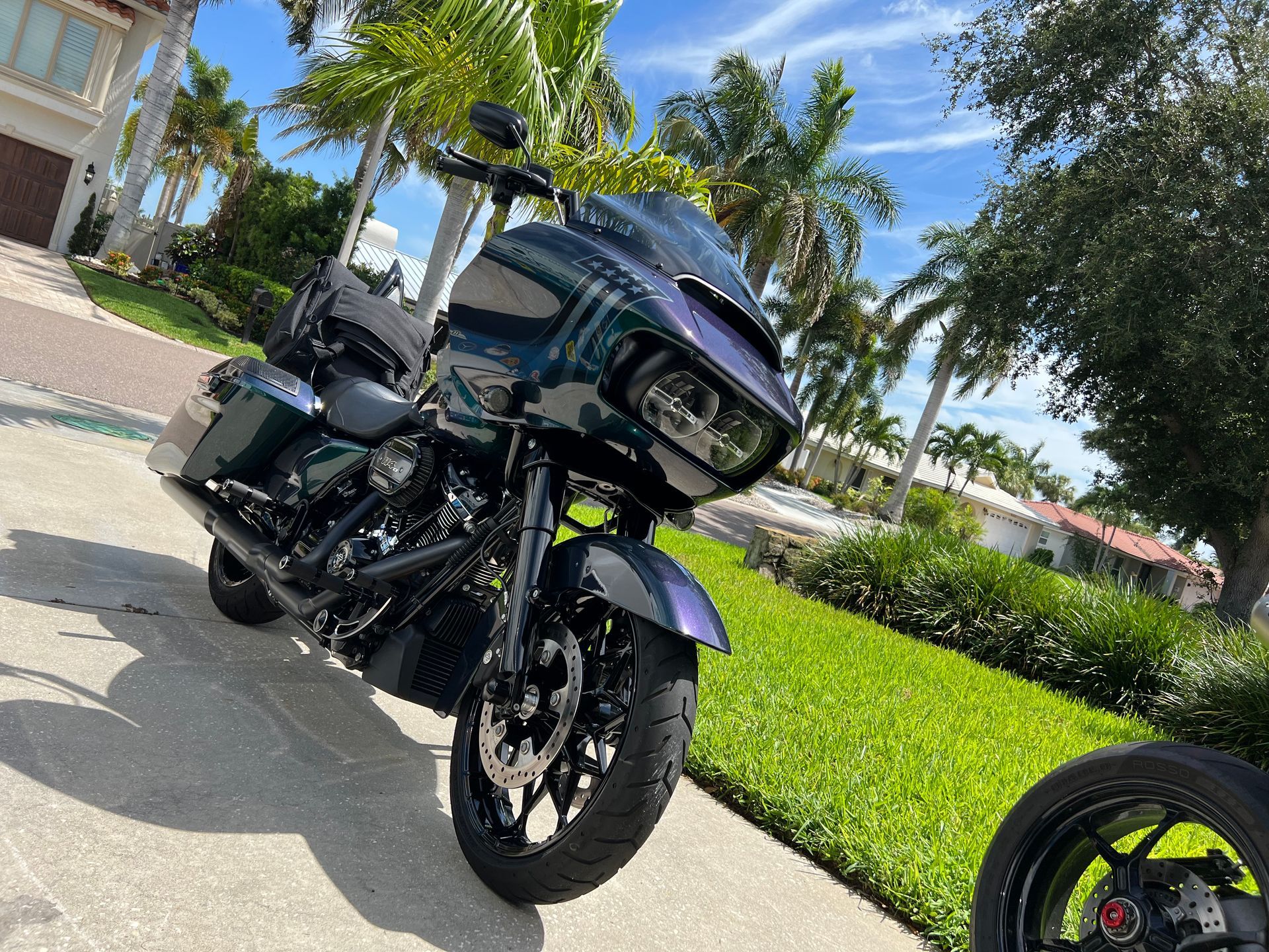 A motorcycle is parked on the side of the road in front of a house.