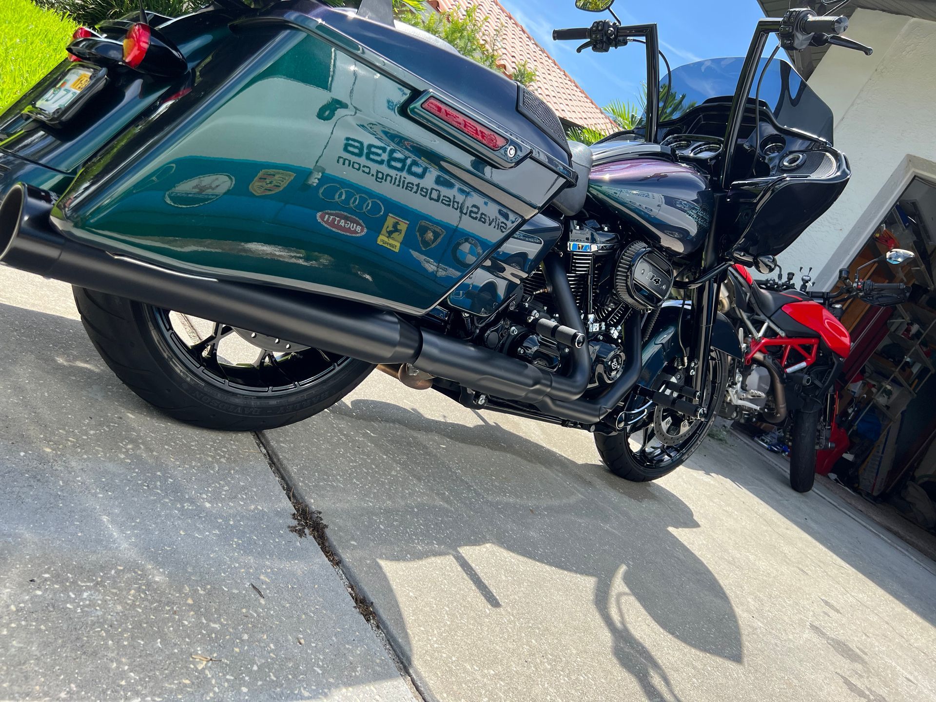 A harley davidson motorcycle is parked on the sidewalk in front of a garage.
