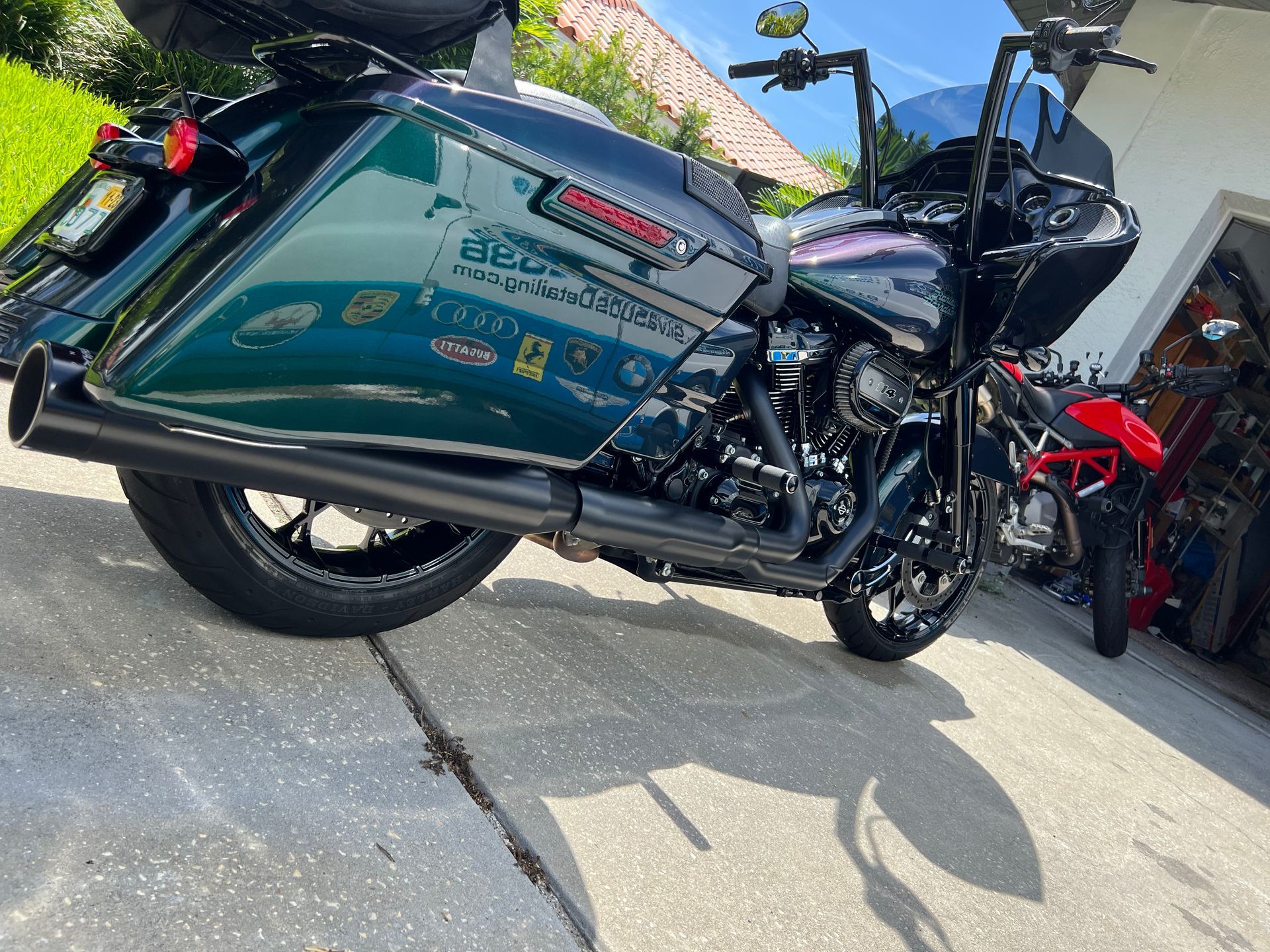 A harley davidson motorcycle is parked on the sidewalk in front of a garage.