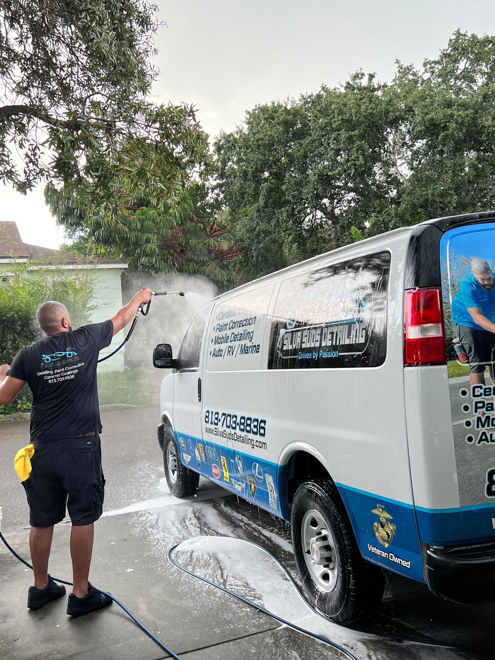 A man is washing a van with a high pressure washer.