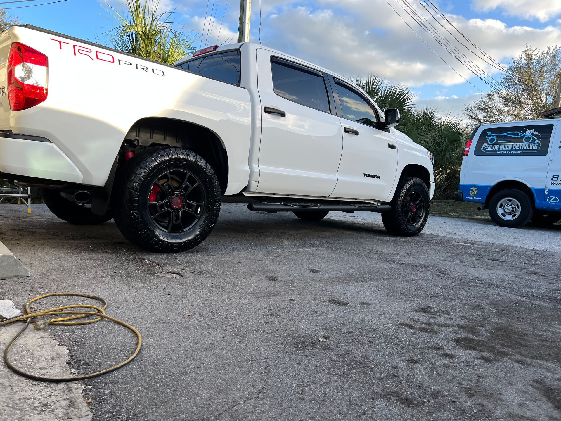 A white truck is parked on the side of the road next to a white van.