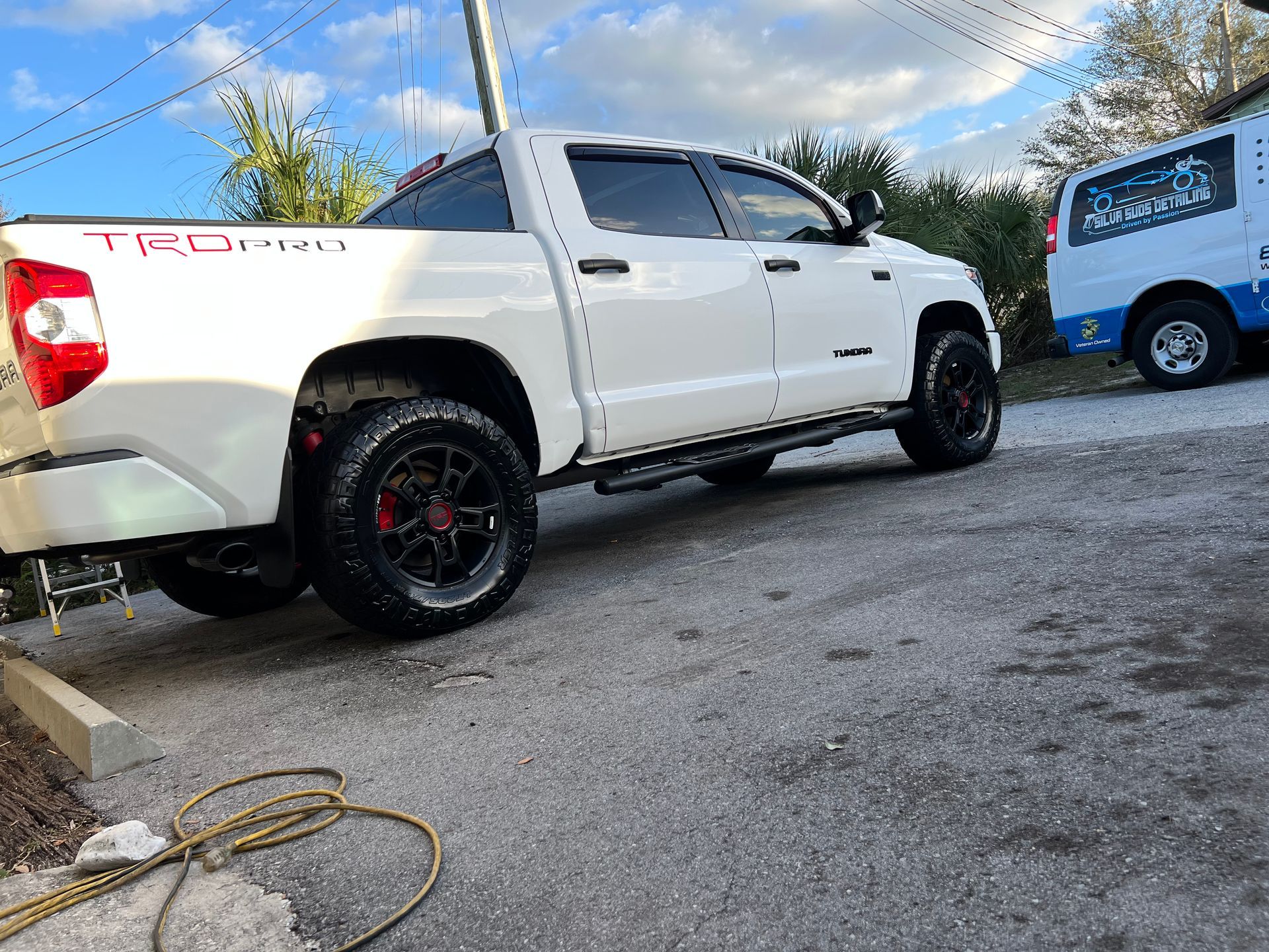 A white truck is parked in a parking lot next to a van.