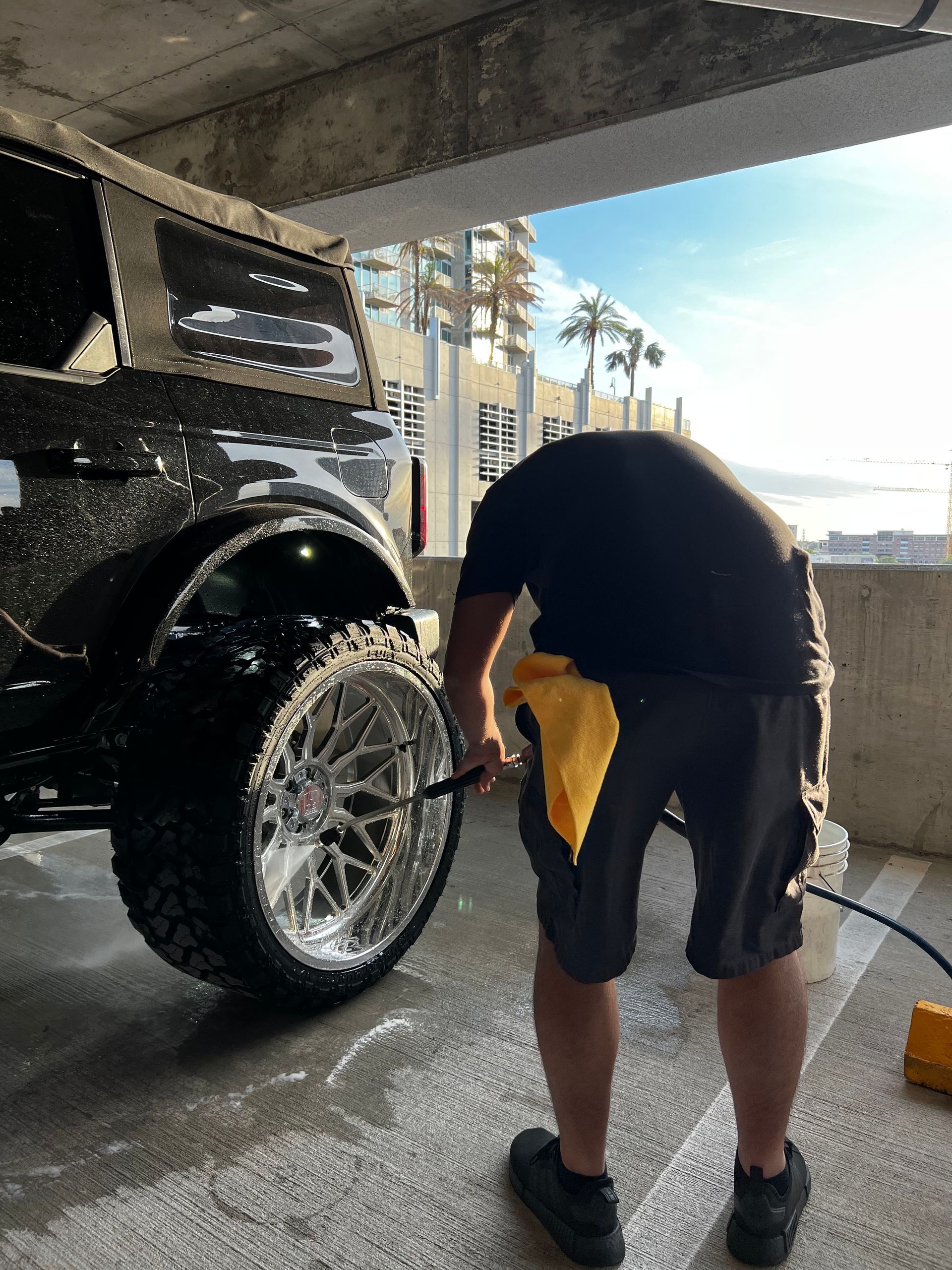 A man is washing a jeep in a parking garage.