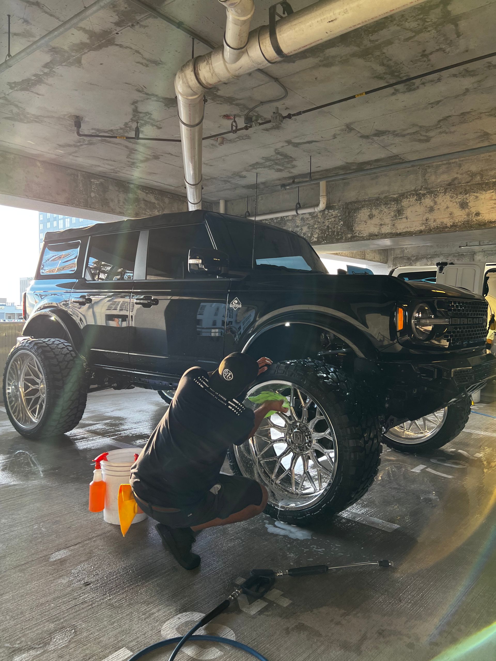A black ford bronco is being washed in a parking garage.