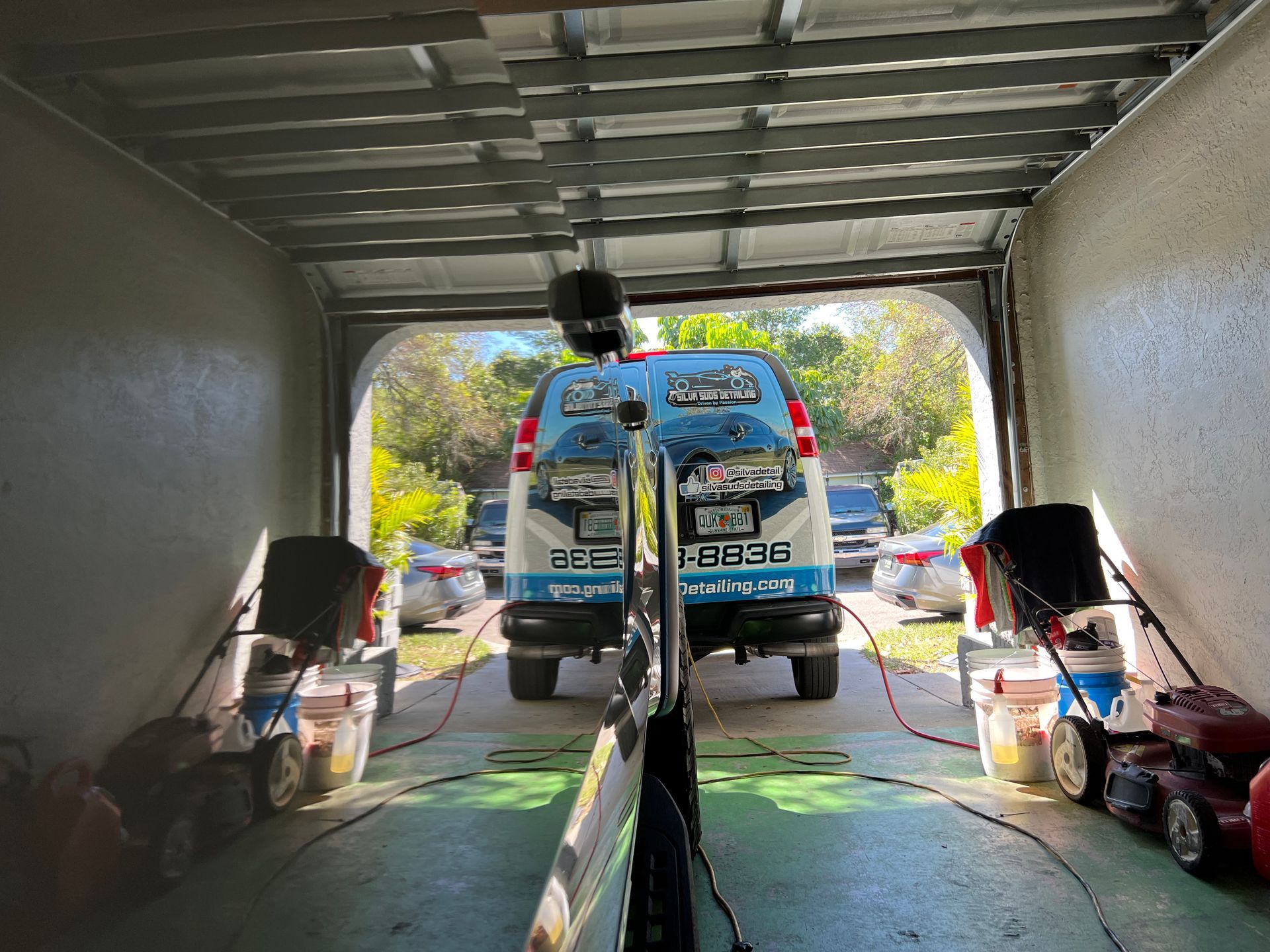 A van is parked in a garage next to a lawn mower.