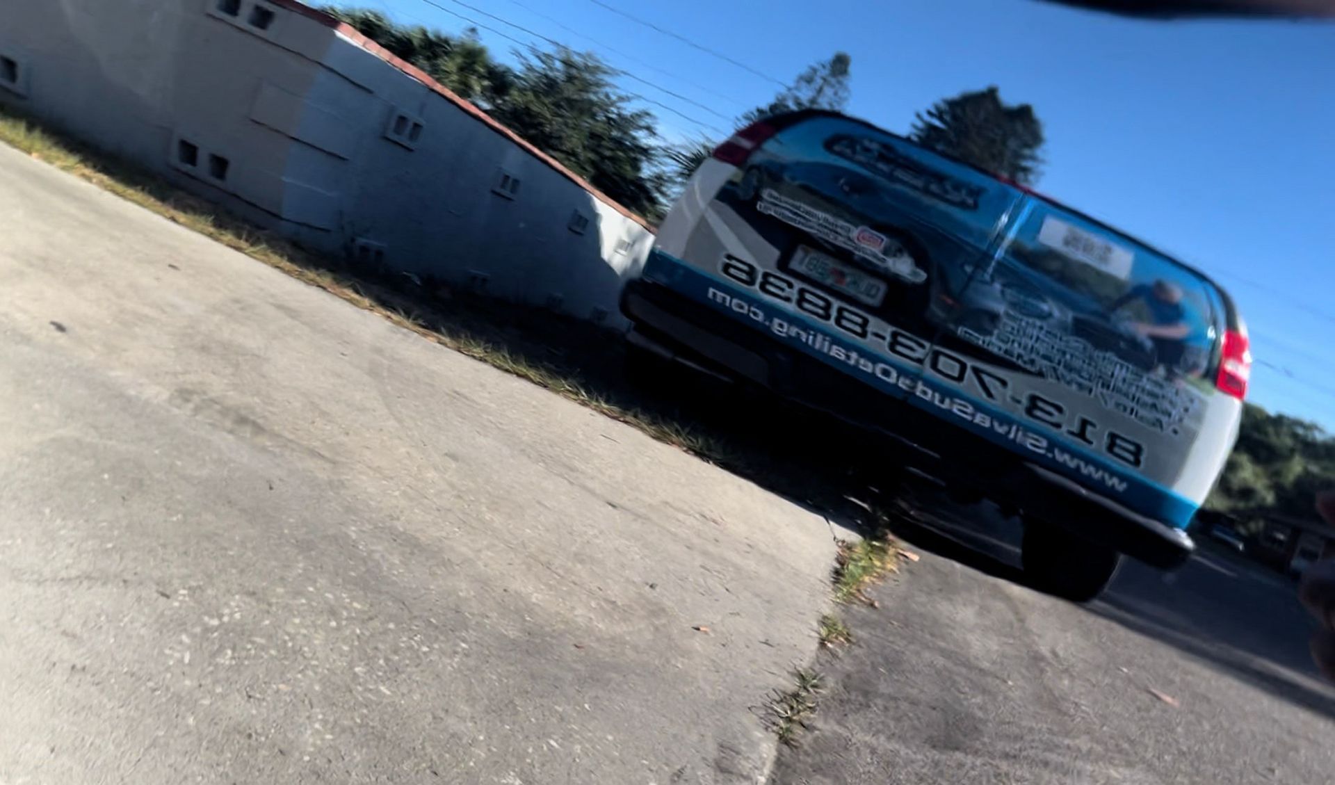 A blue and white van is parked on the side of the road.