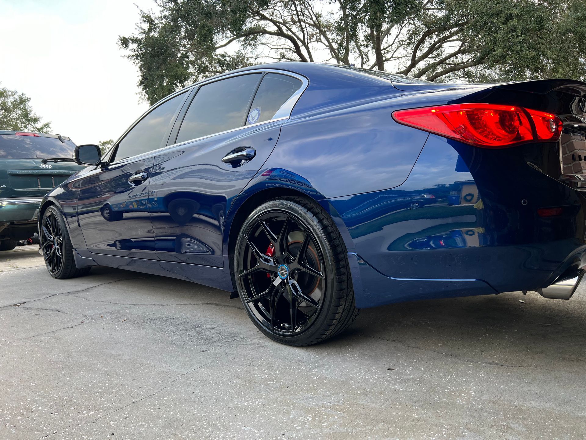 A blue car with black wheels is parked on the side of the road.