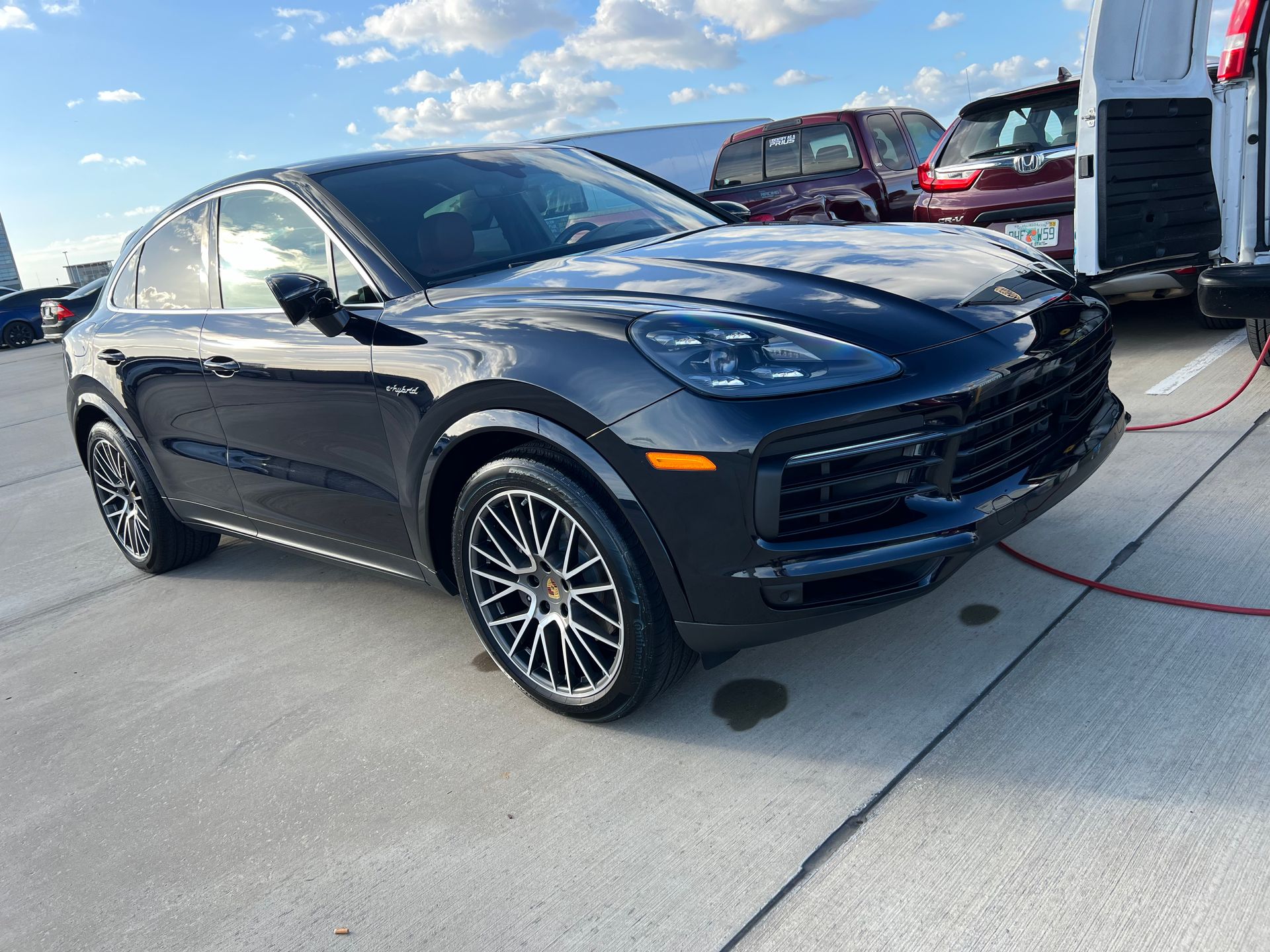 A black porsche cayenne turbo is parked in a parking lot next to a van.