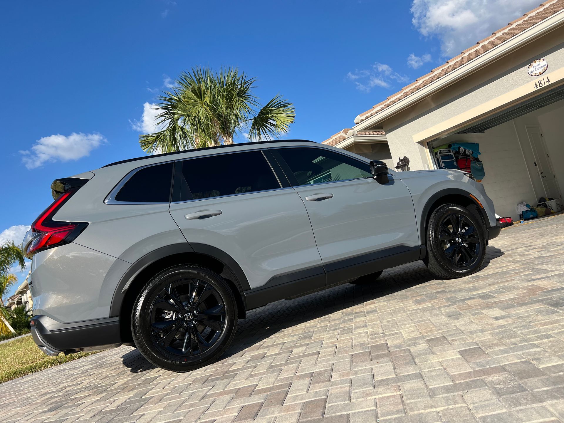 A gray suv is parked on a brick driveway in front of a house.