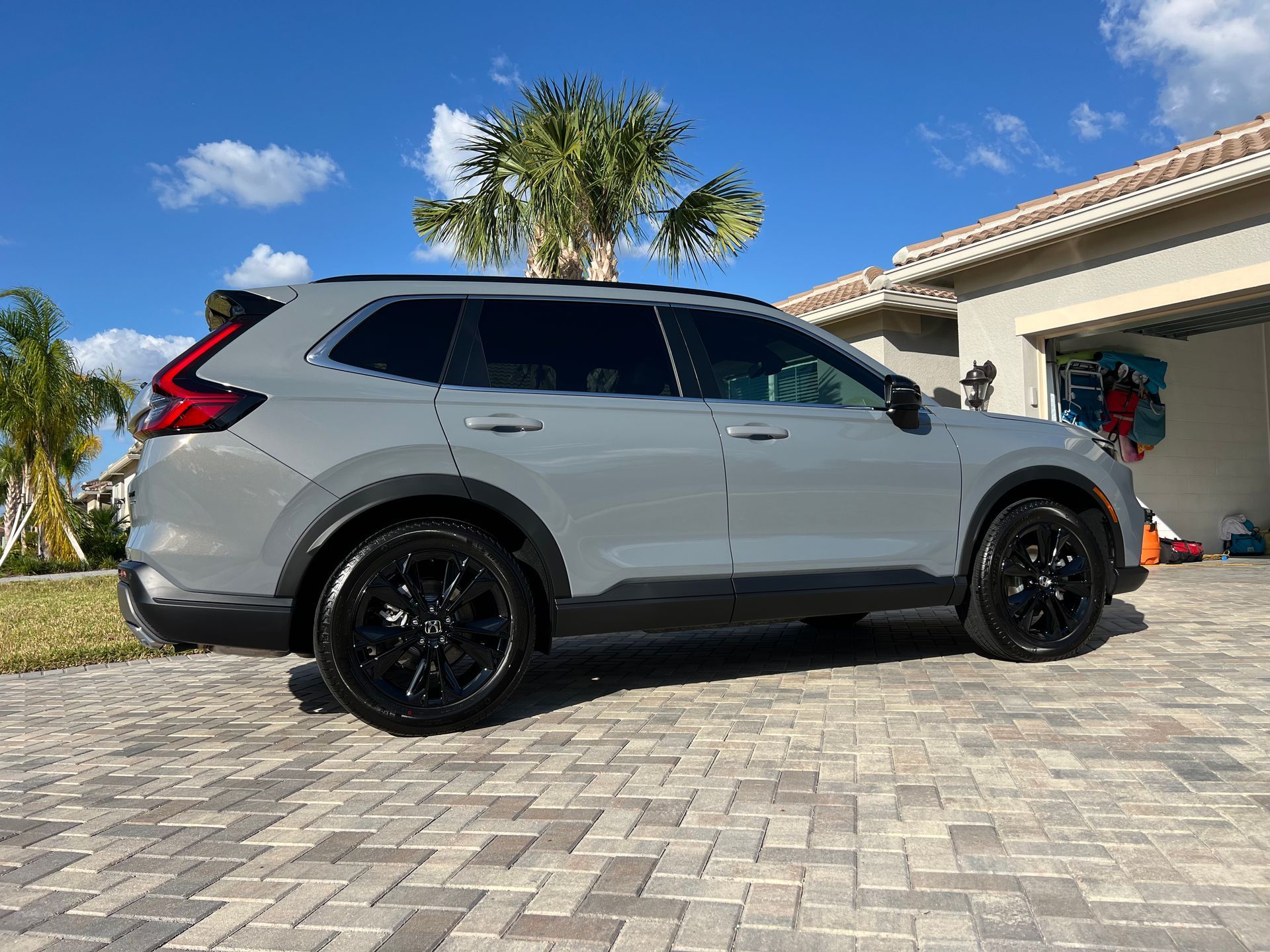 A gray suv is parked on a brick driveway in front of a house.