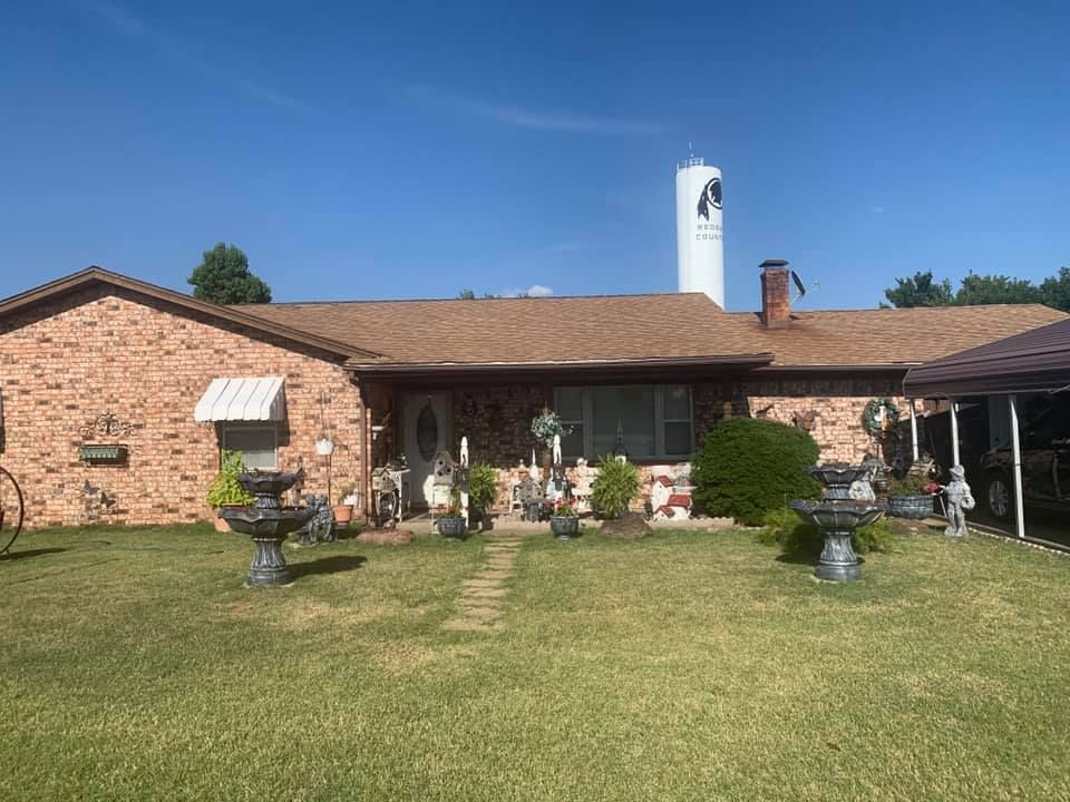 A brick house with a silo in the background and a fountain in front of it.